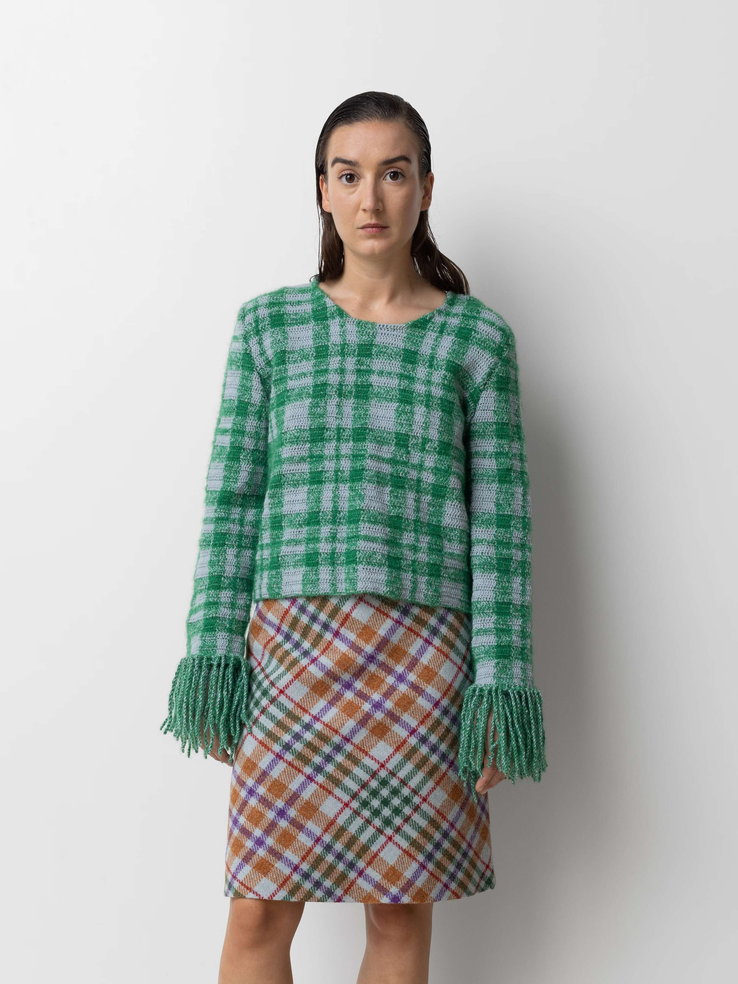 Picture of a femle model wearing a colourful wool skirt in combination with a green wool pullover