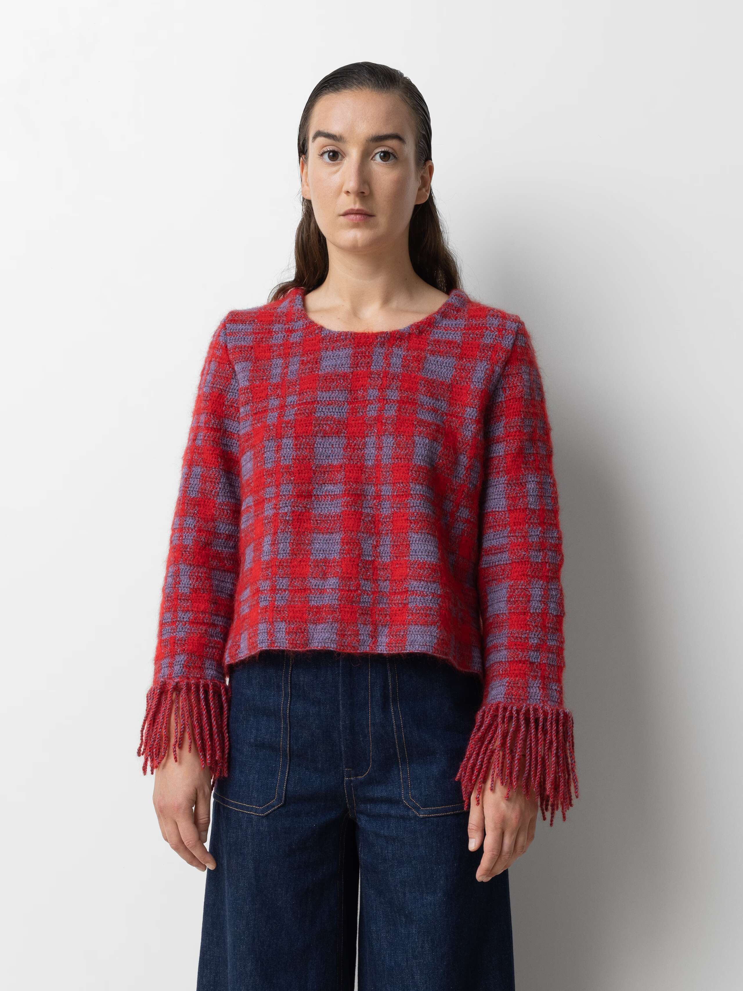 Picture of a female model wearing a red wool pullover in combination with a jeans 
