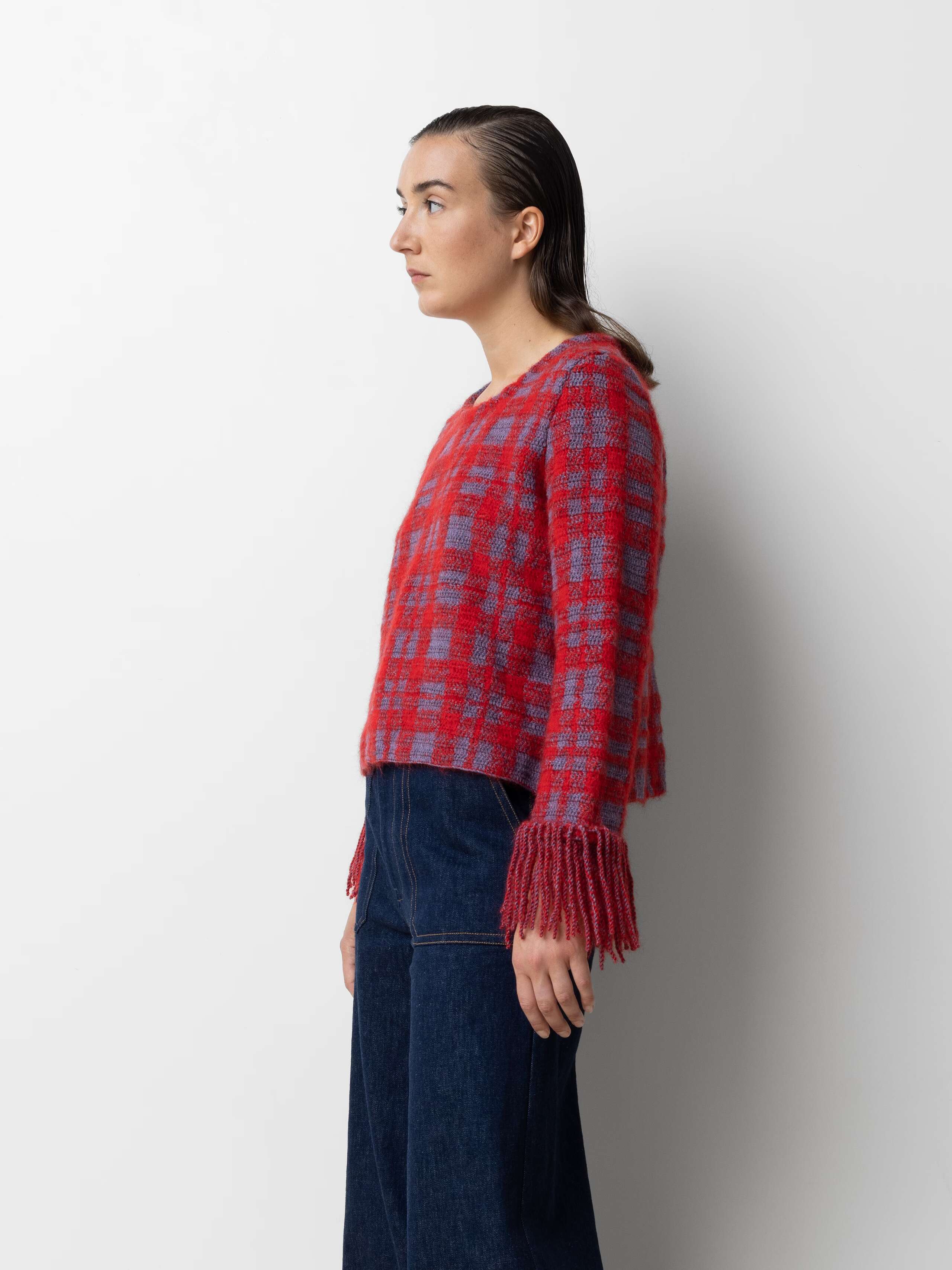 Picture of a female model wearing a red wool pullover in combination with a jeans 