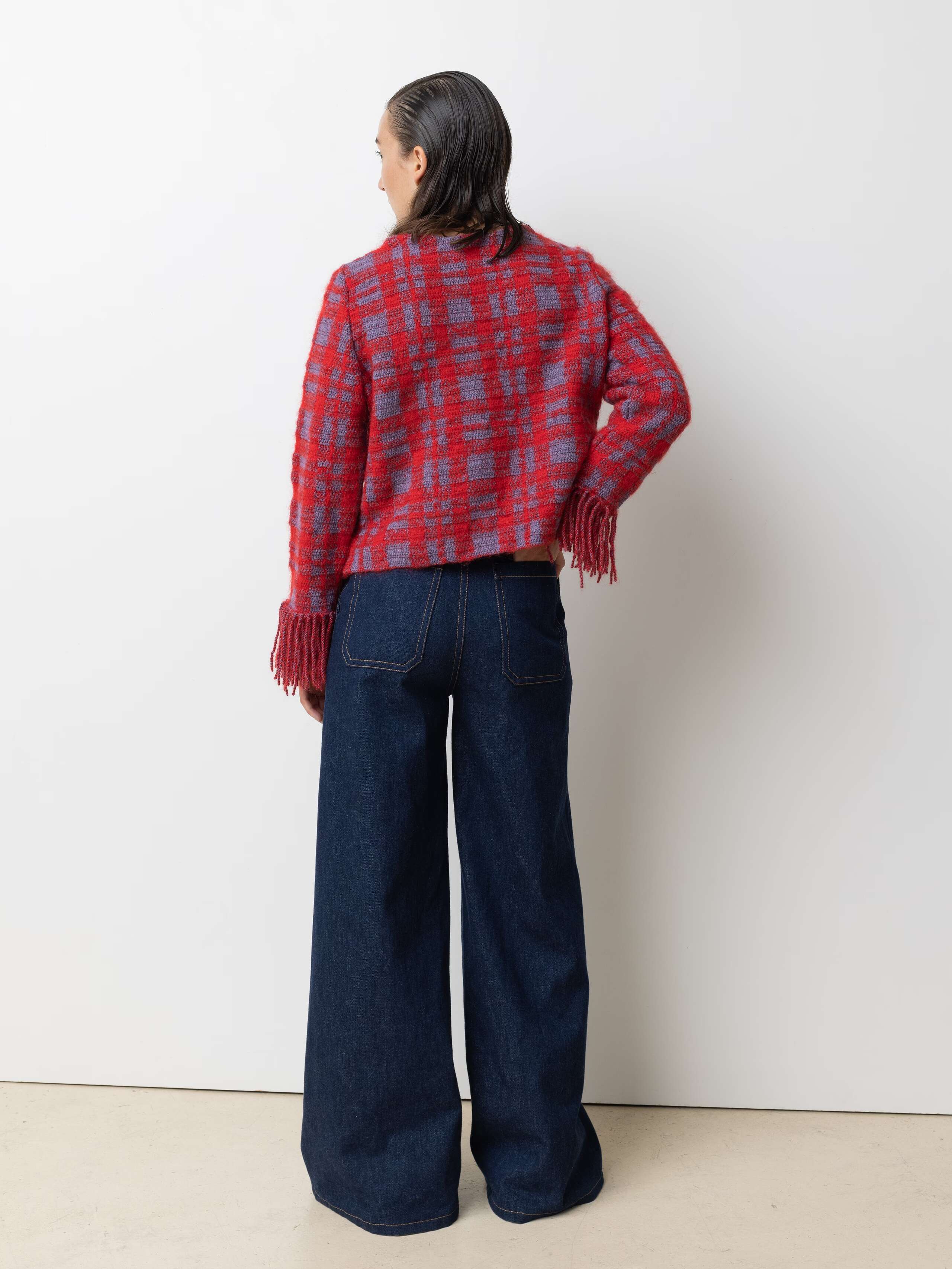 Picture of a female model wearing a red wool pullover in combination with a jeans 