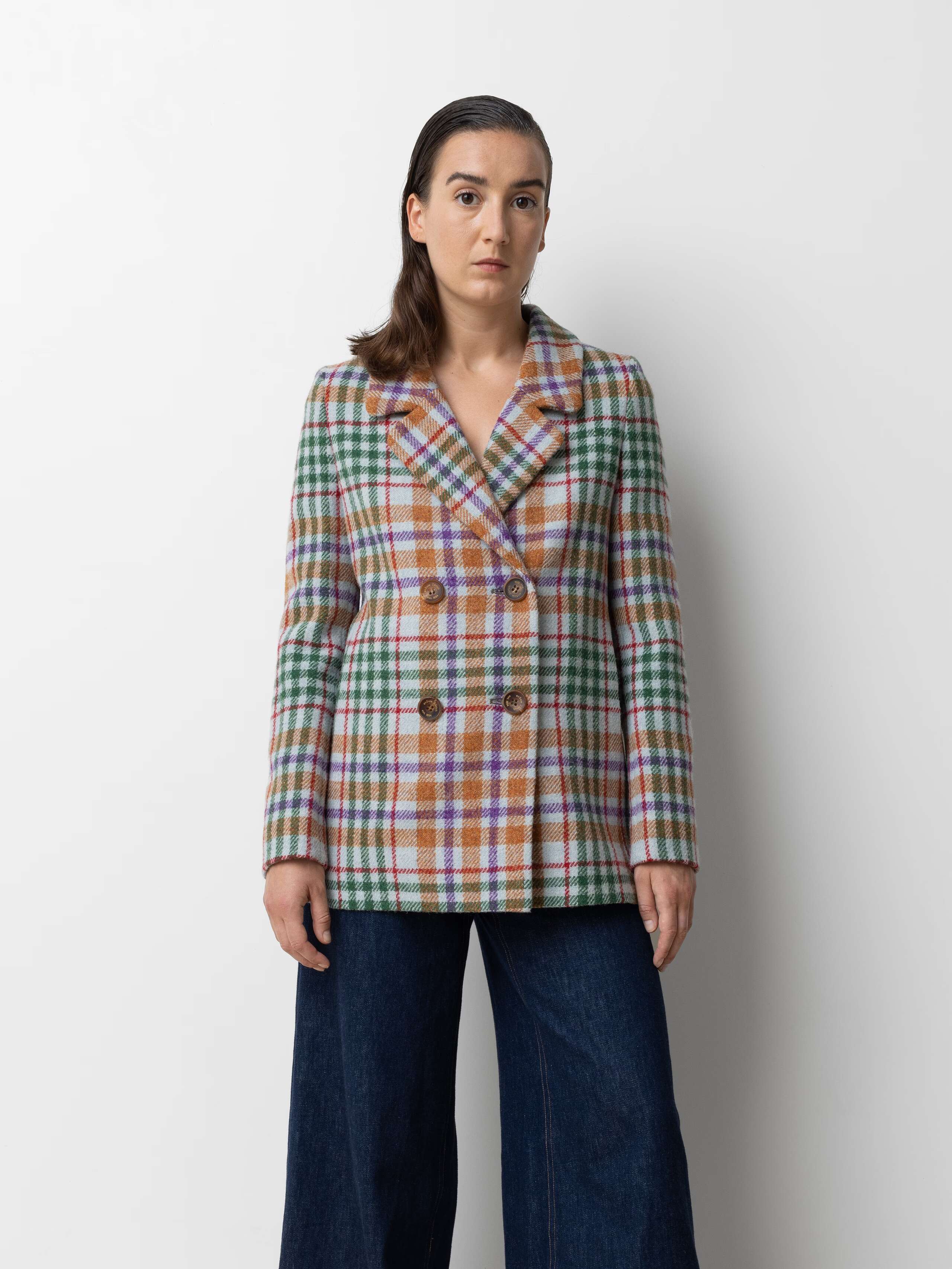 Picture of a female model wearing a colourful wool blazer in combination with a wide leg jeans