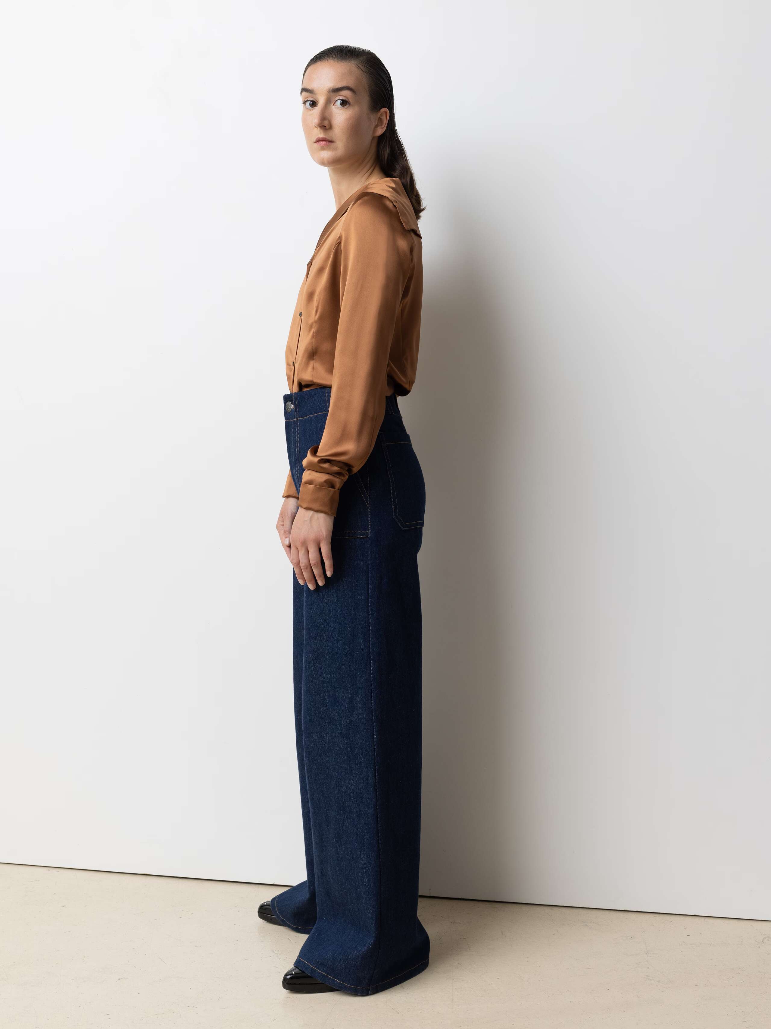Picture of a female model wearing blue jeans in combination with a shiny brown silk blouse
