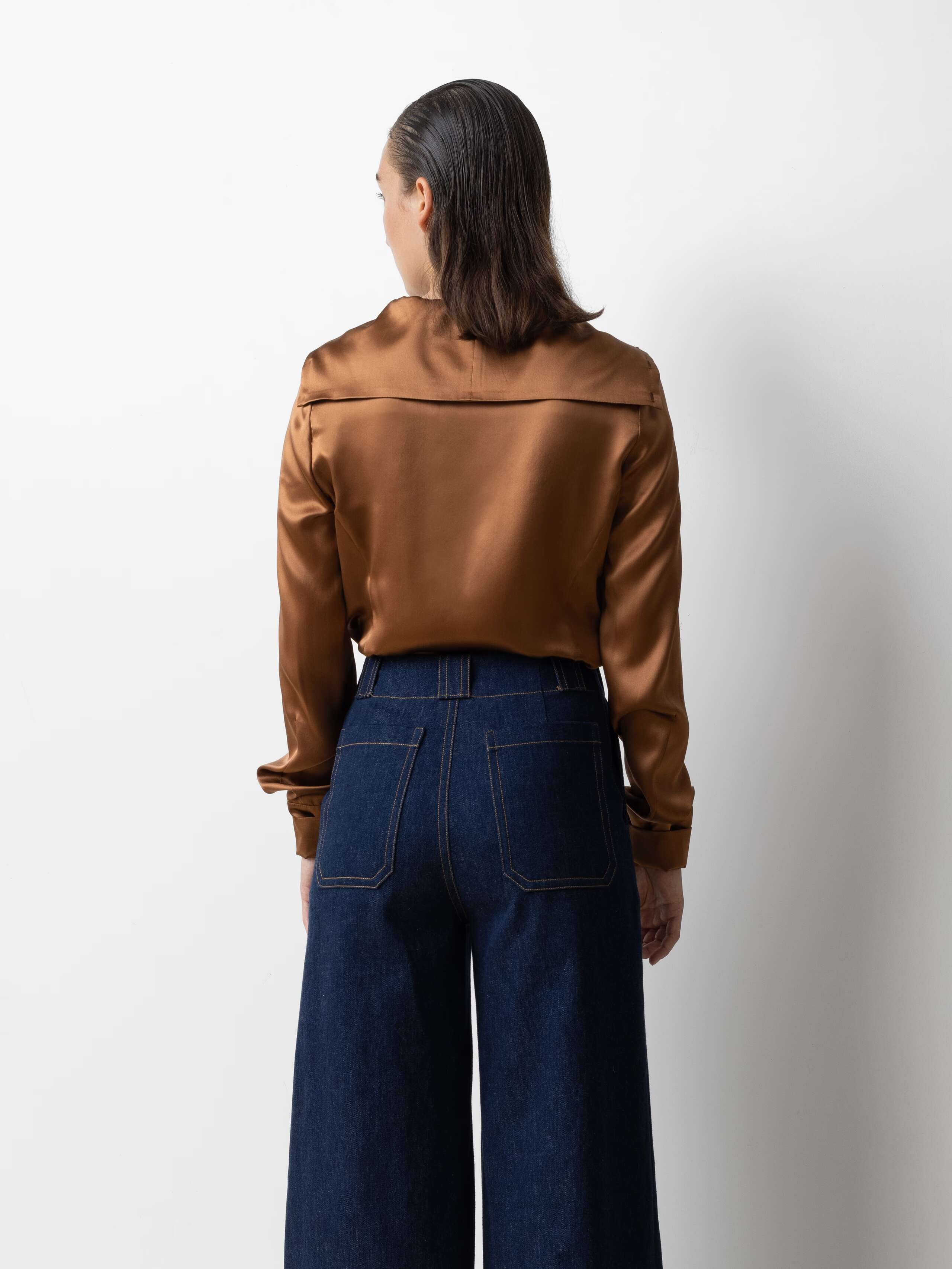 Picture of a female model wearing blue jeans in combination with a shiny brown silk blouse
