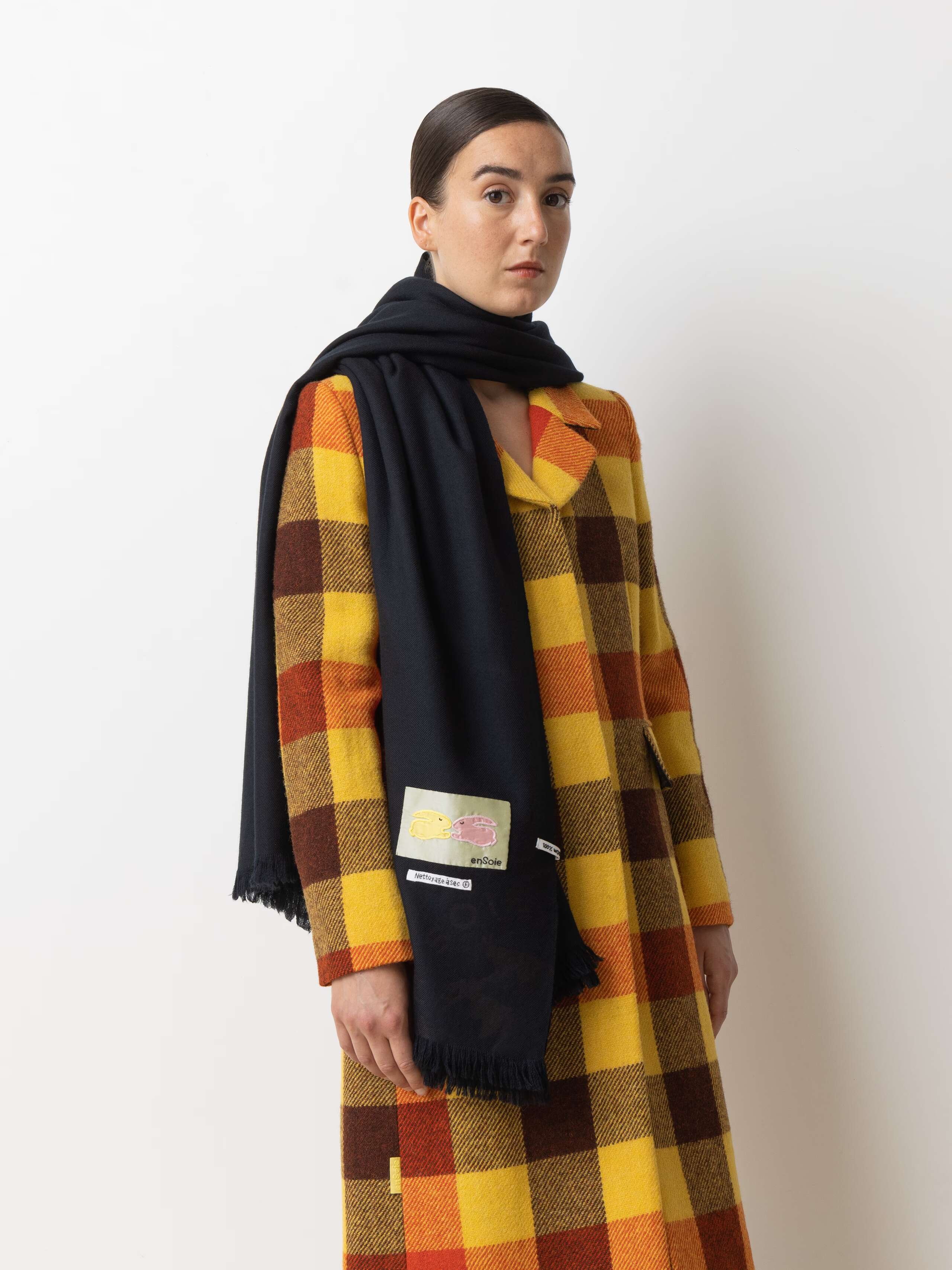 Picture of a female model wearing a colourful winter coat in combination with a black wool scarf