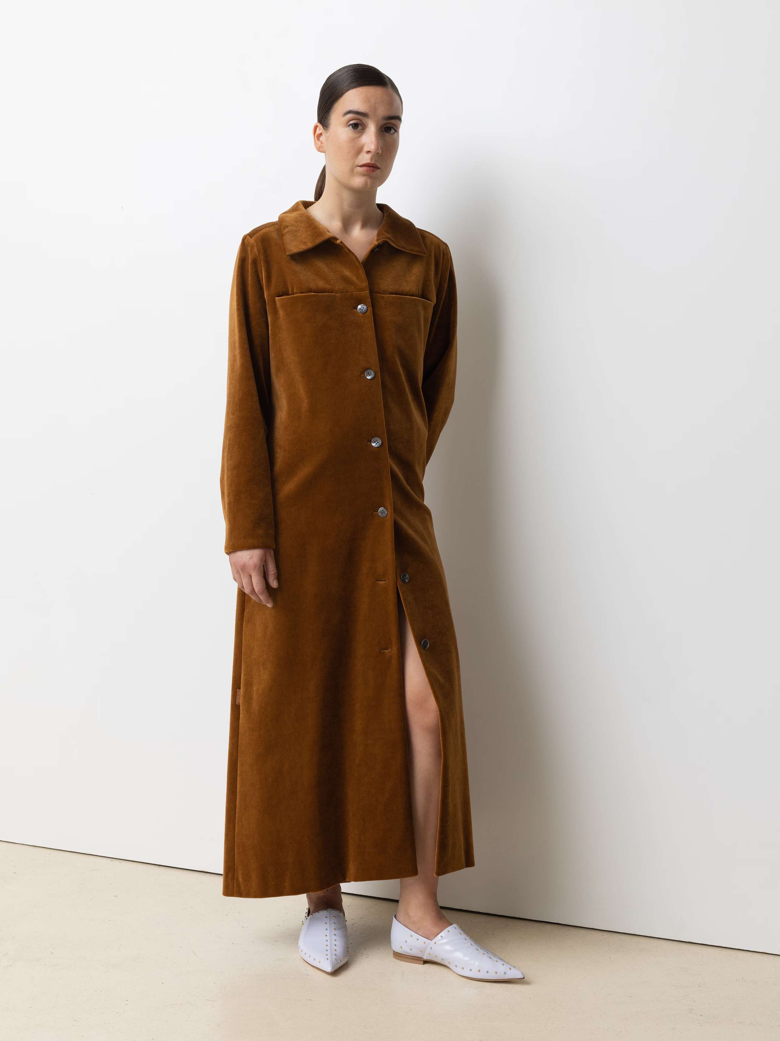 Picture of a female model wearing a long velvet dress in a warm brown shade