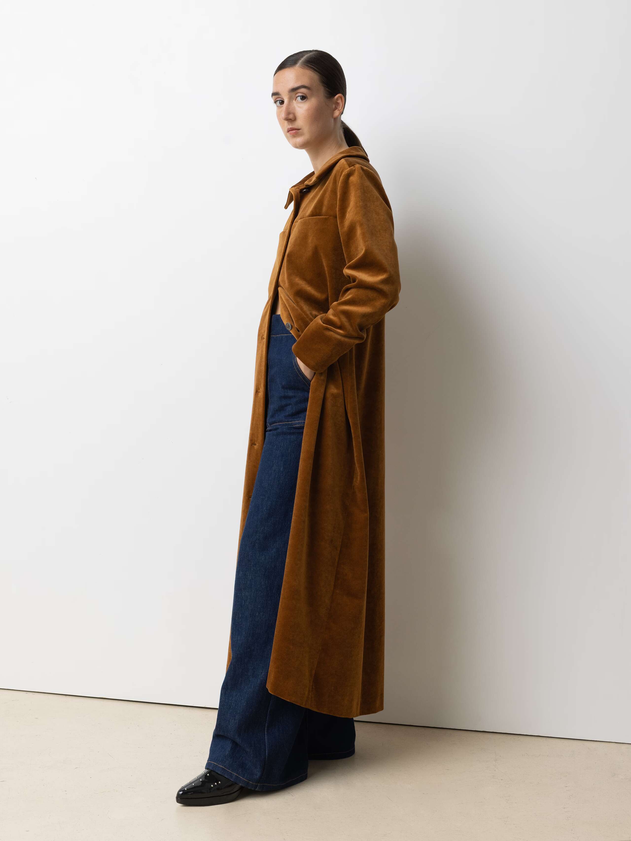 Picture of a female model wearing a long velvet dress in a warm brown shade