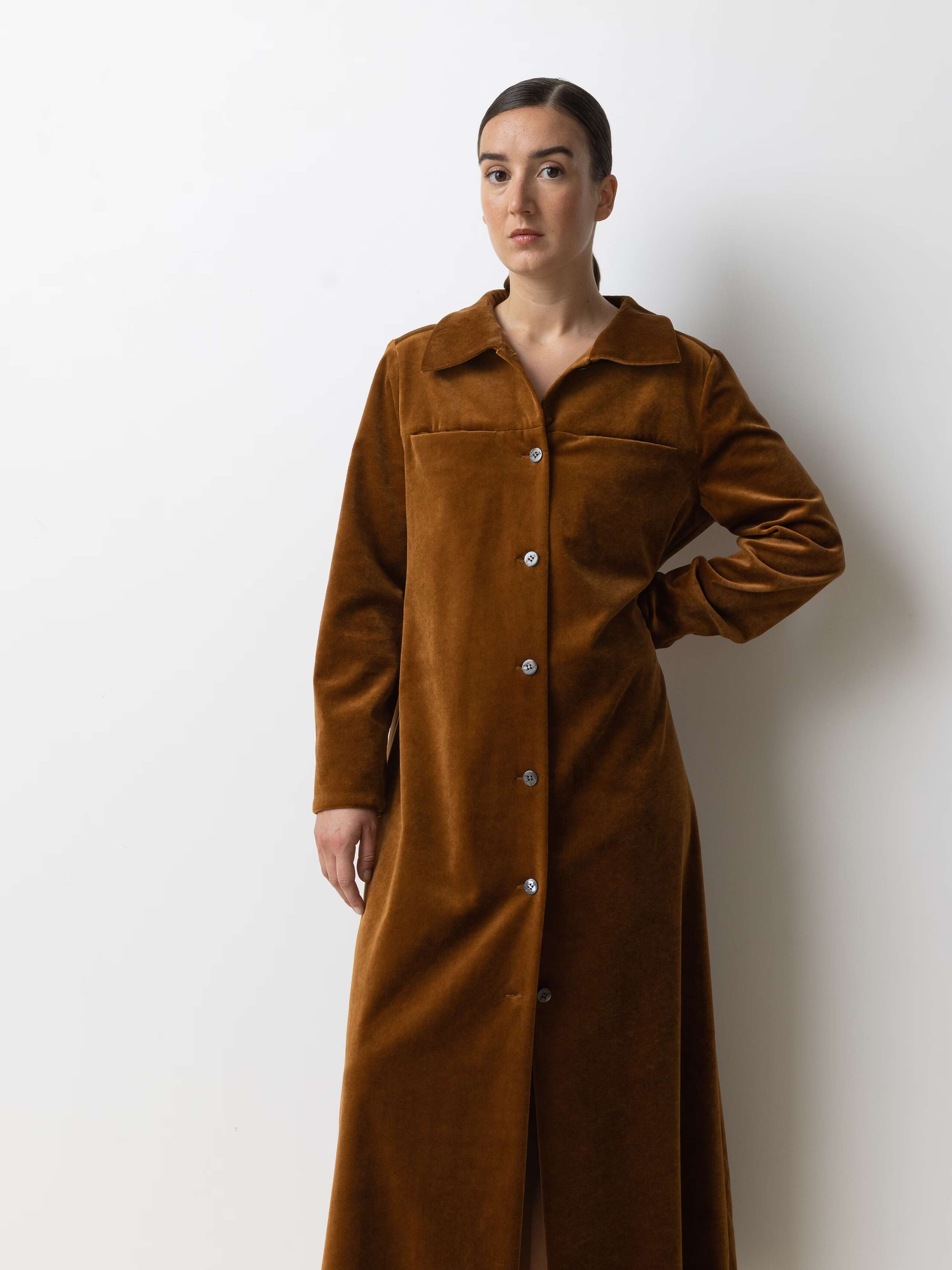 Picture of a female model wearing a long velvet dress in a warm brown shade