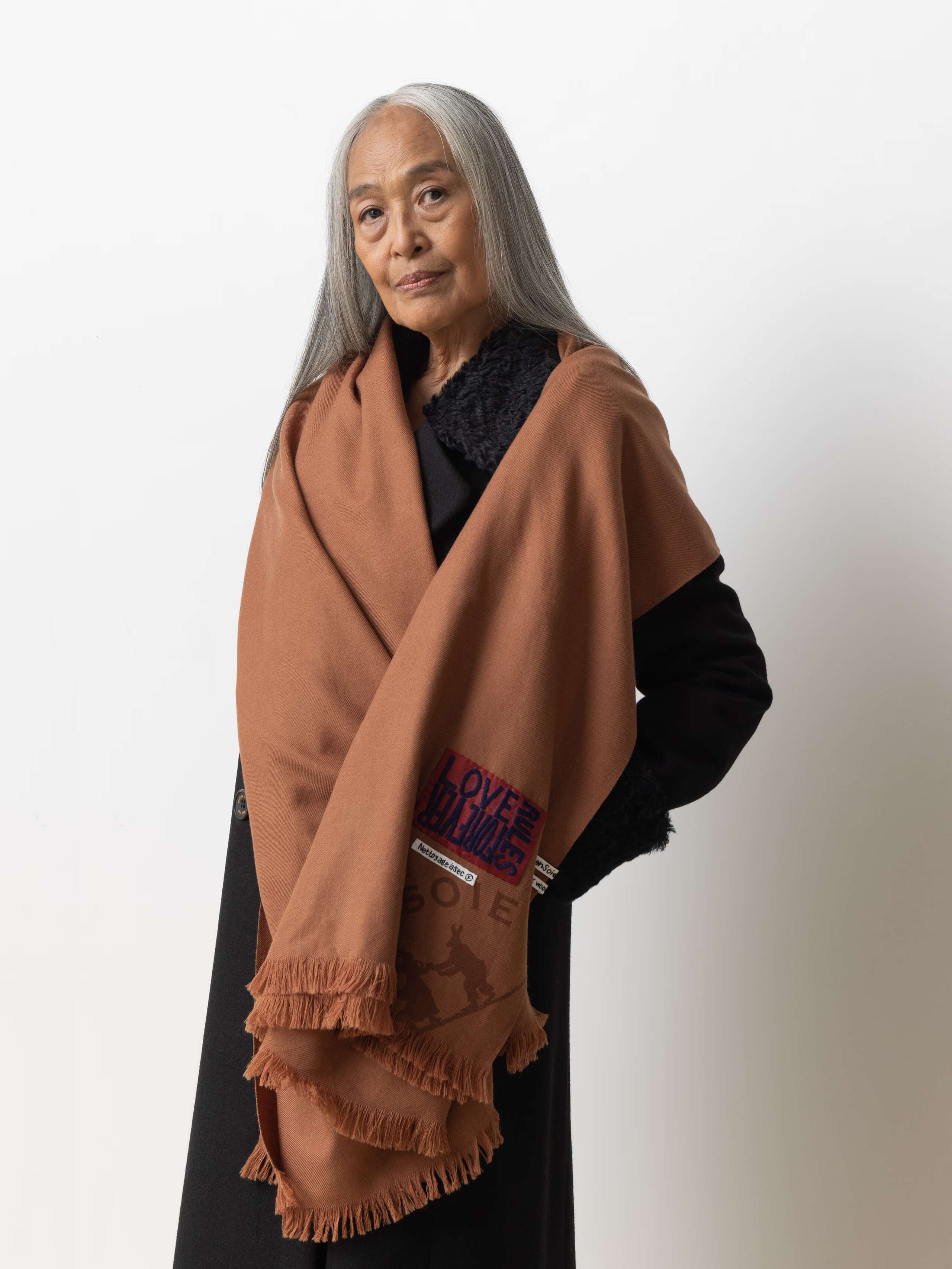 Picture of a female model wearing a black wool coat in combination with a brown wool scarf