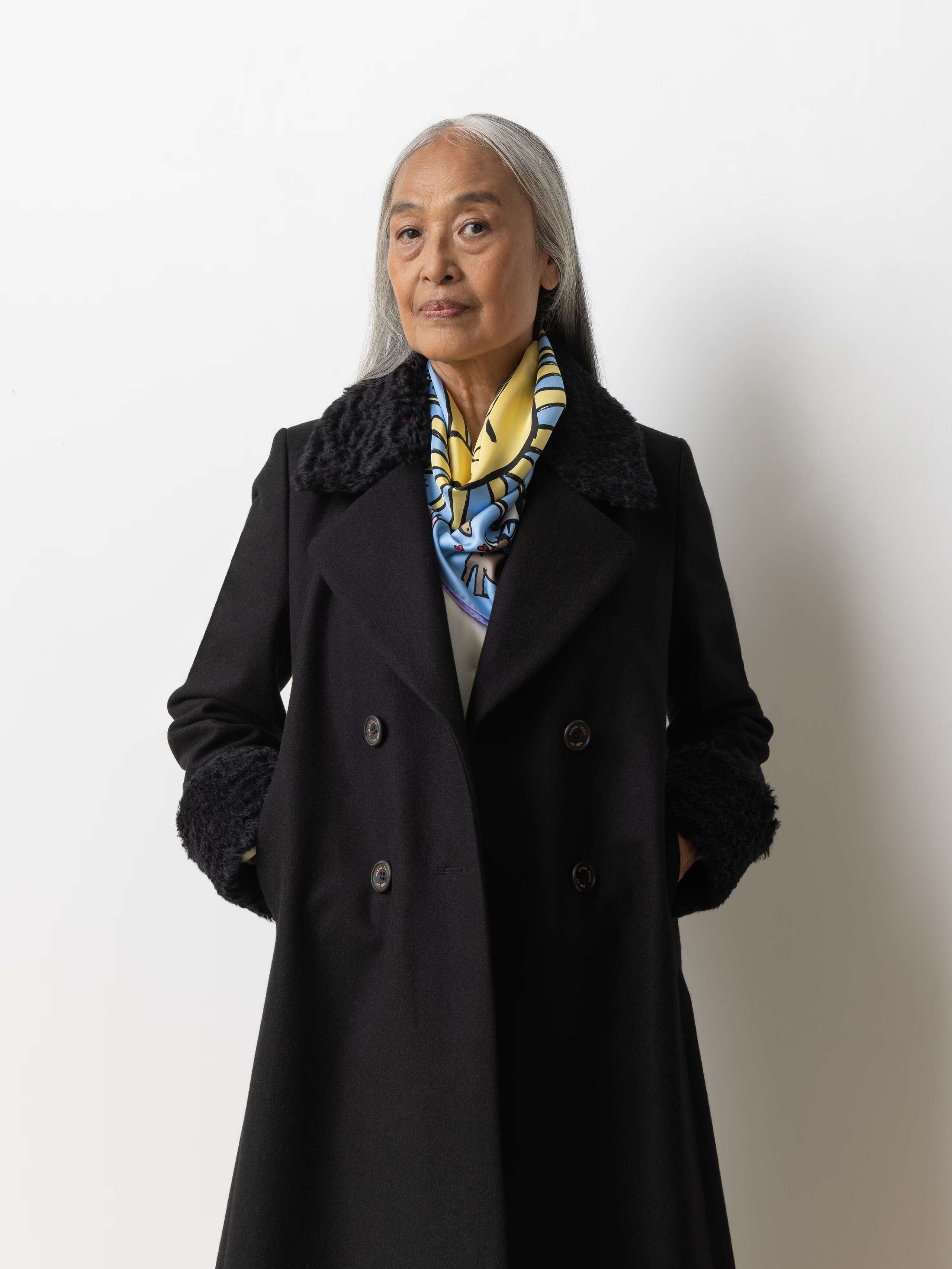 Picture of a female model wearing a black wool coat in combination with a light blue silk foulard