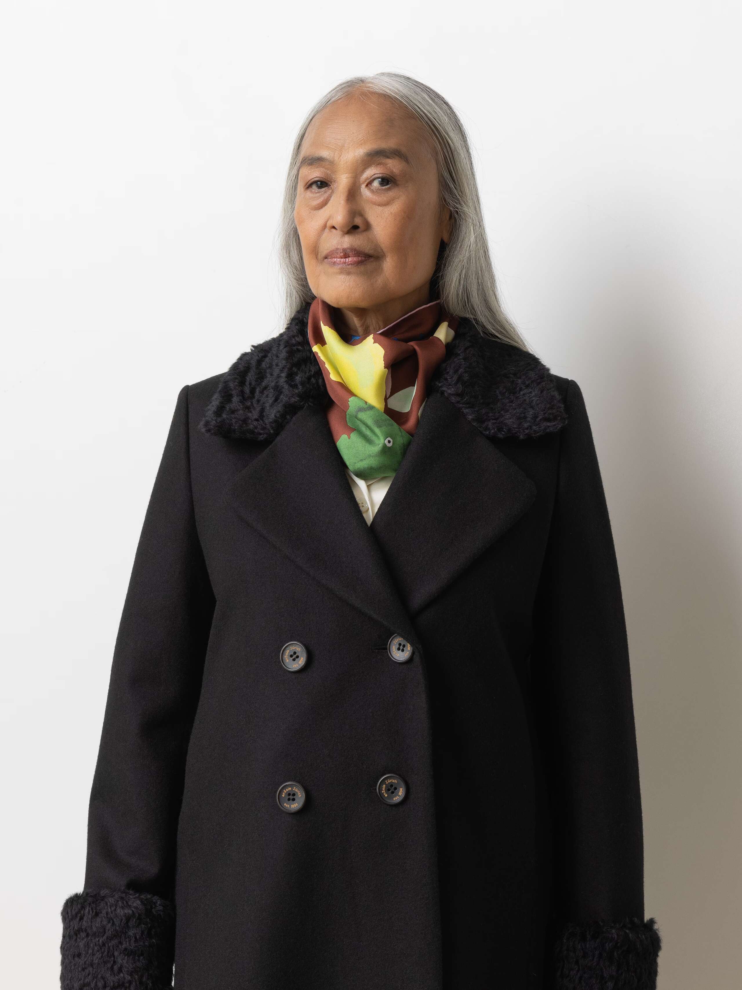 Picture of a female model wearing a black wool coat in combination with a brown silk foulard