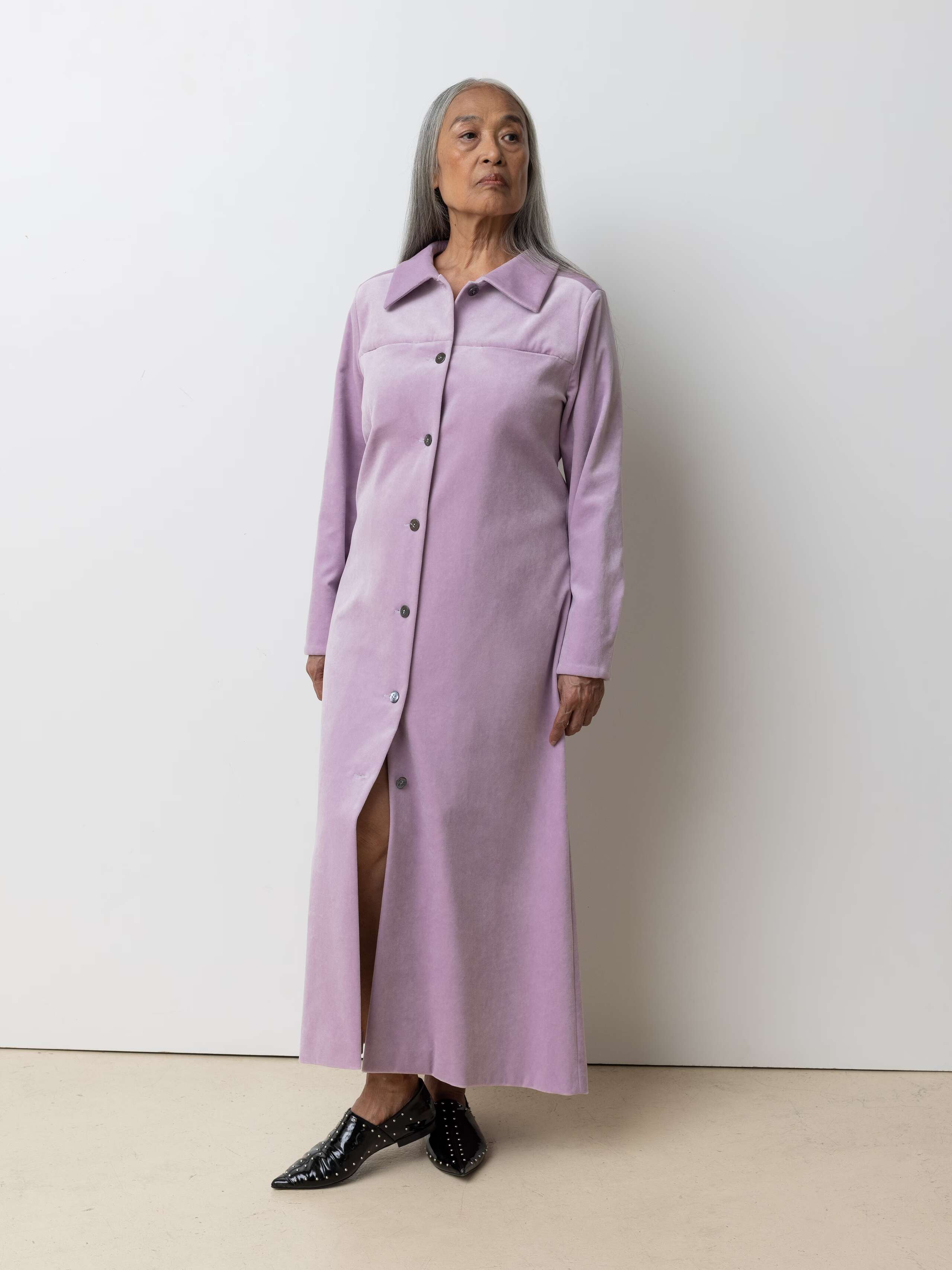 Picture of a female model wearing a long velvet dress in a delicate lavender shade