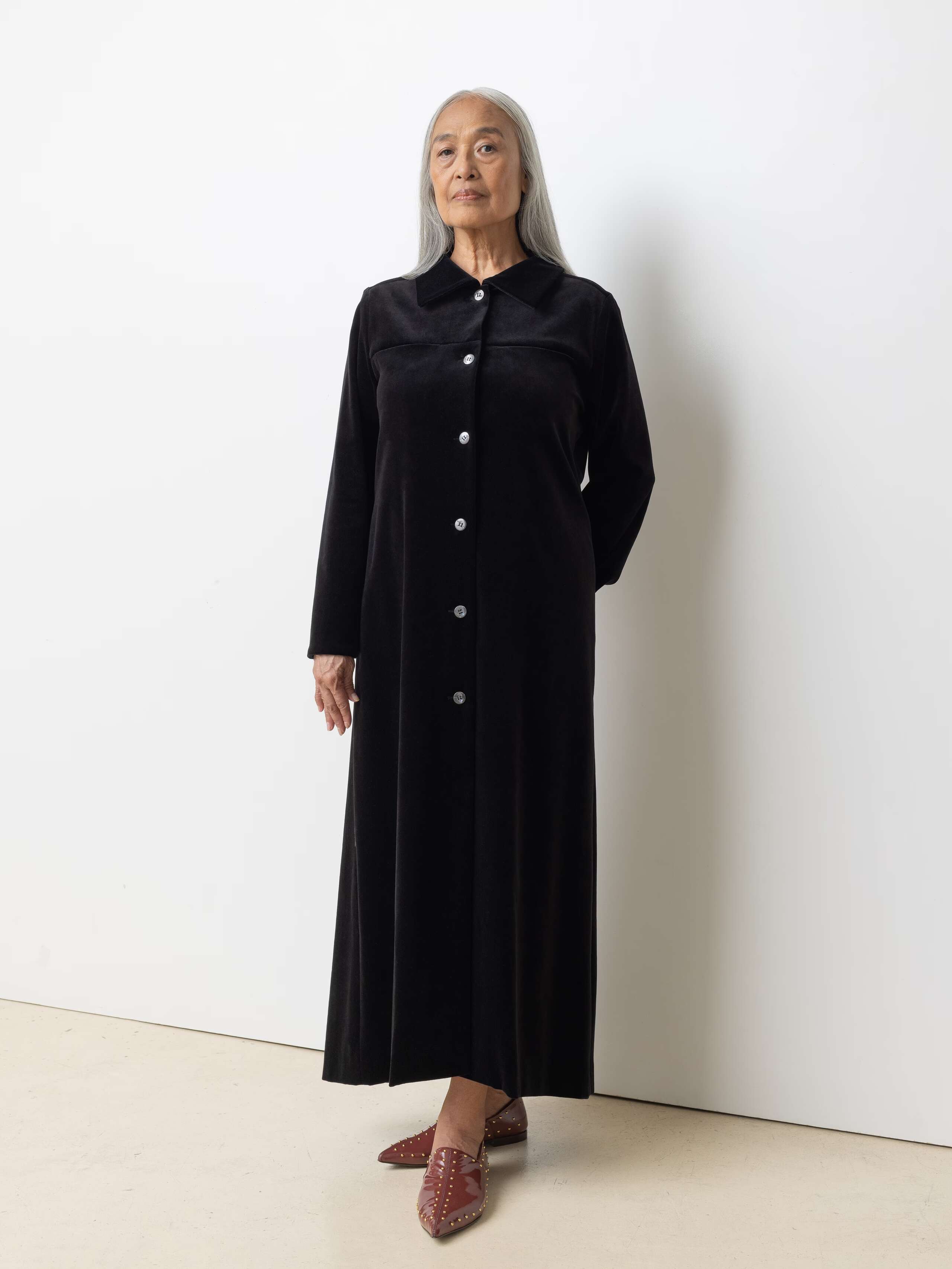 Picture of a female model wearing a long velvet dress in classic black