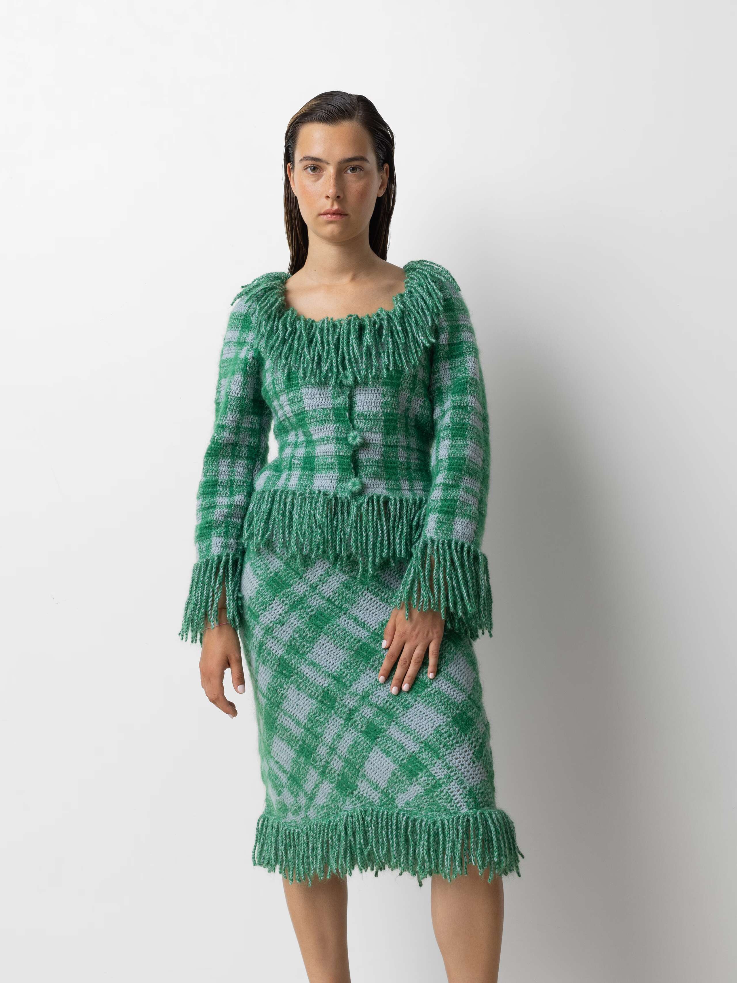 Picture of a female model wearing a combination of a greenish wool cardigan and matching skirt