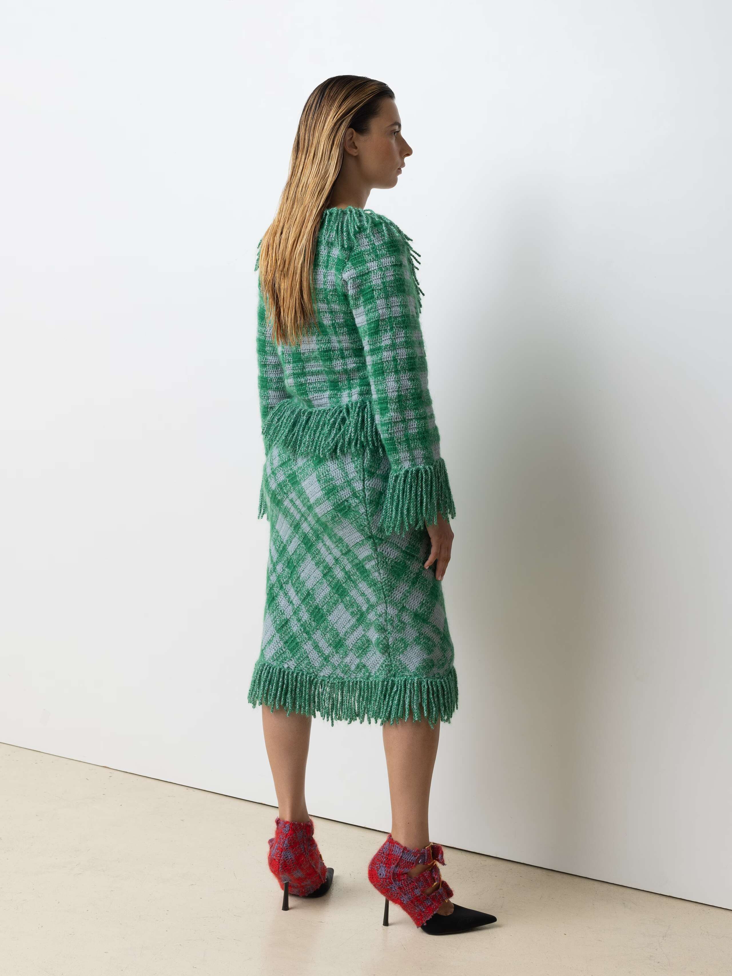 Picture of a female model wearing a combination of a greenish wool cardigan and matching skirt