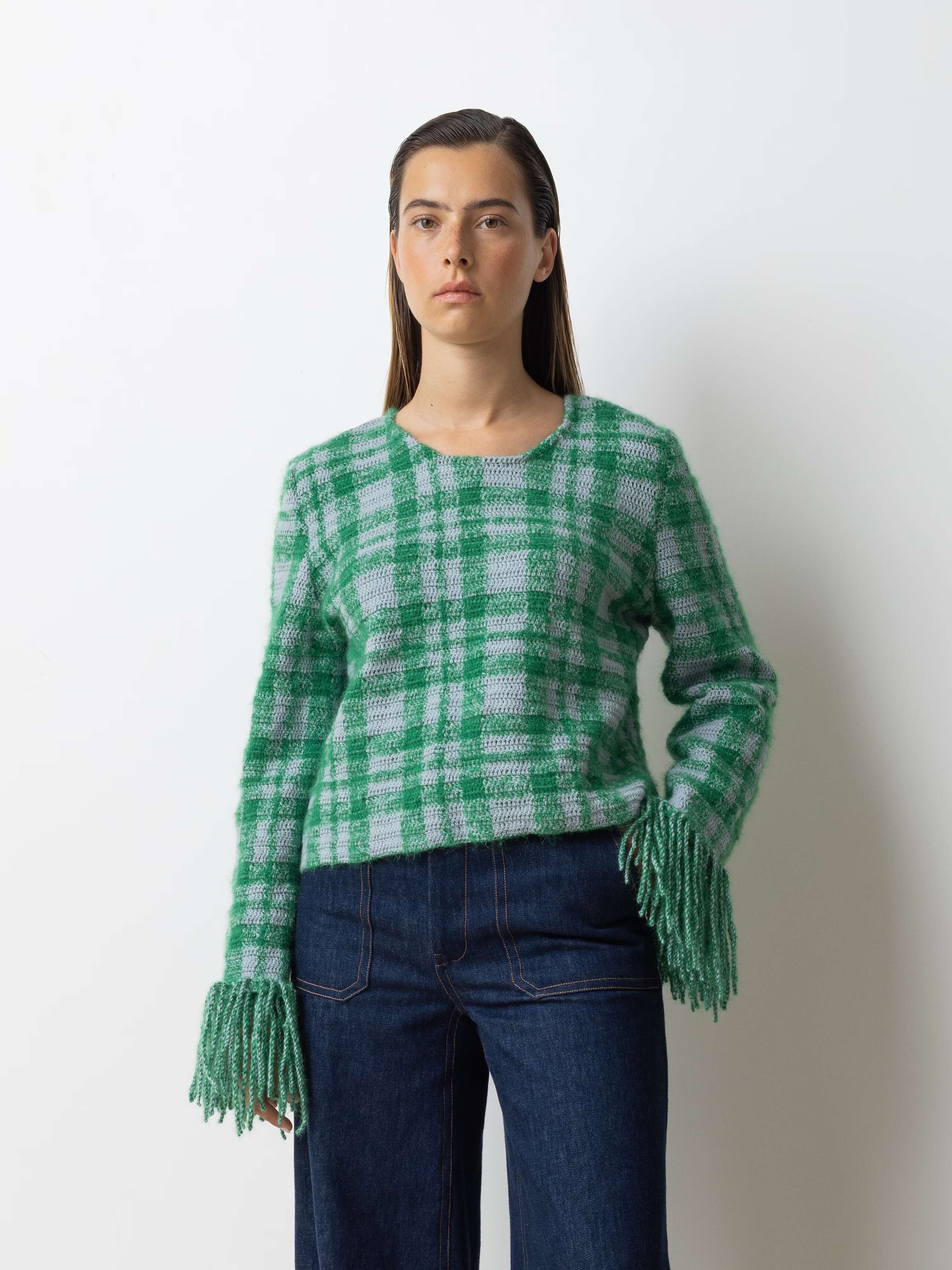 Picture of a female model wearing a combination of a greenish wool pullover and a jeans
