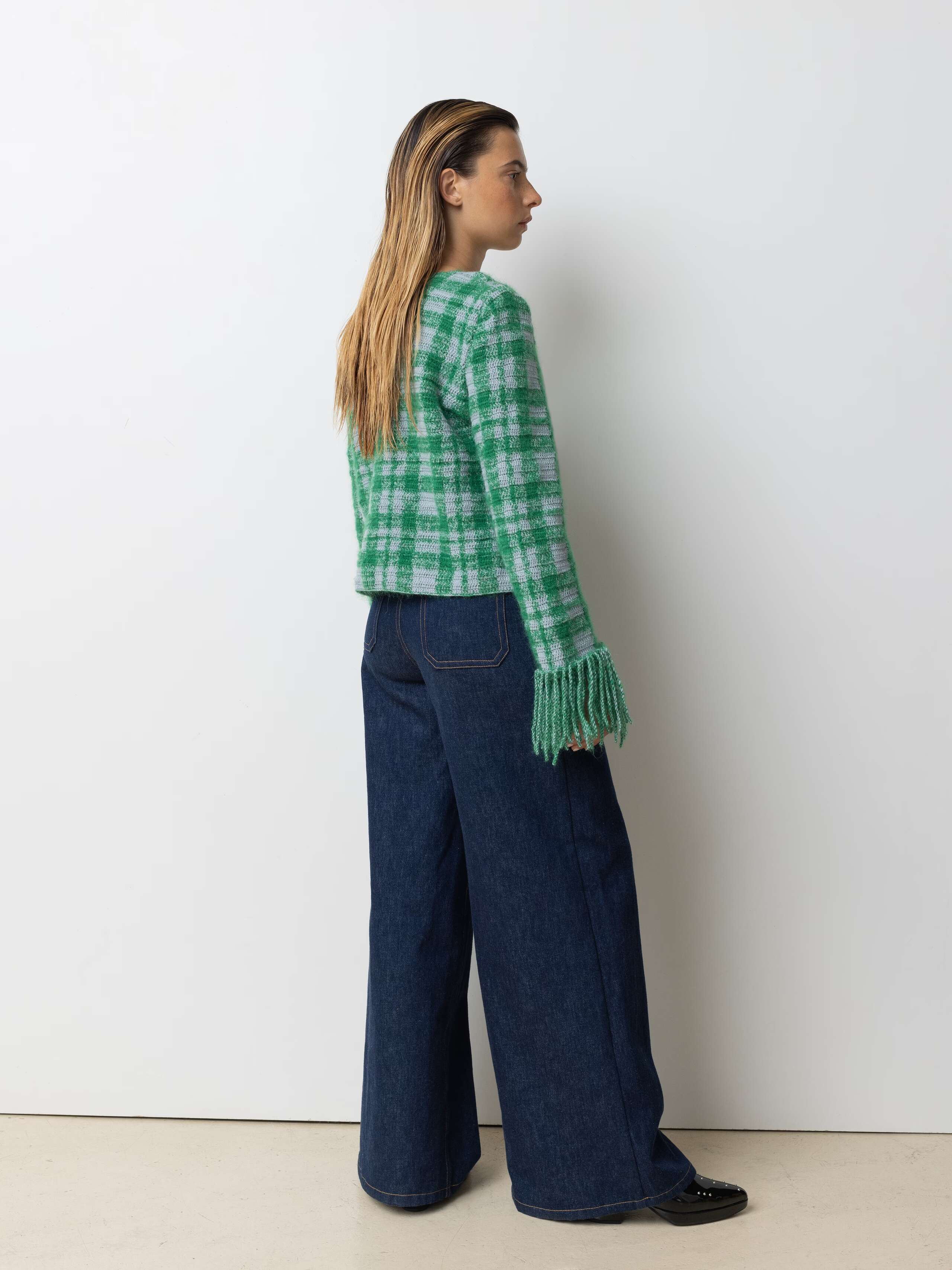 Picture of a female model wearing a combination of a greenish wool pullover and a jeans
