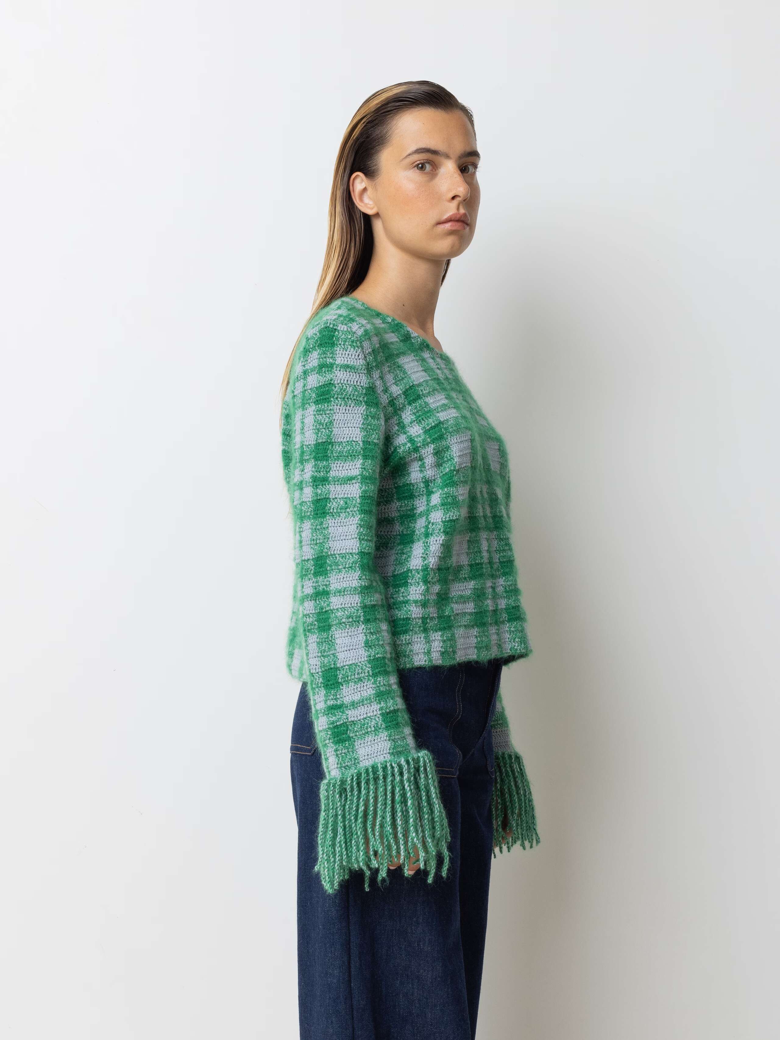 Picture of a female model wearing a combination of a greenish wool pullover and a jeans