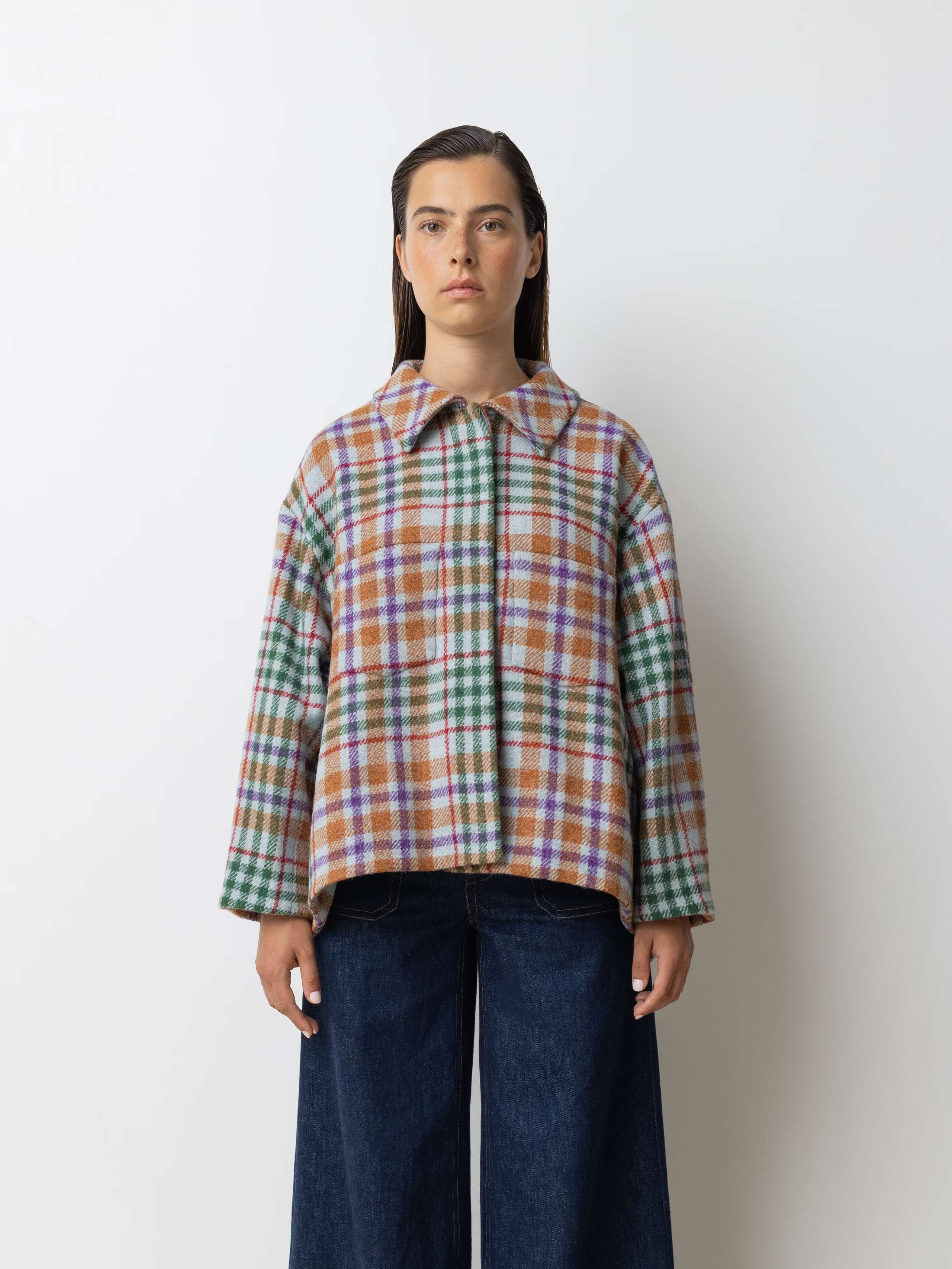 Picture of a female model wearing a wide colourful wool jacket in combination with a wide leg jeans