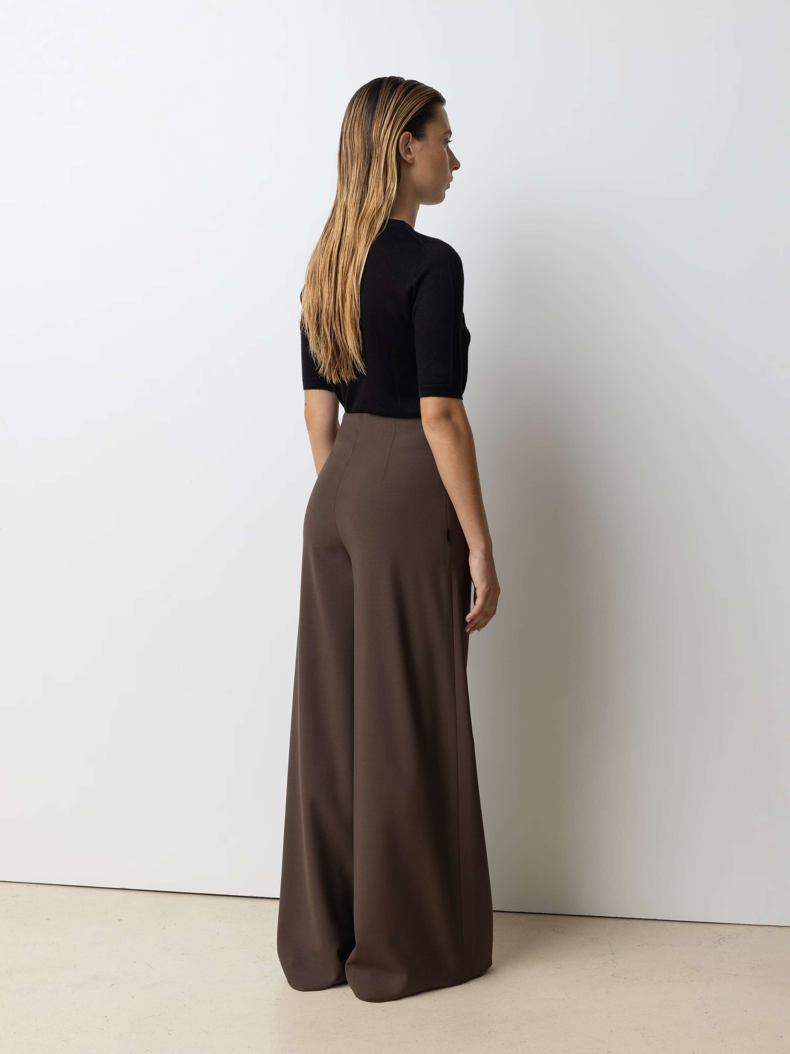 Picture of a female model wearing a classic black turtleneck in combination with brown wool pants