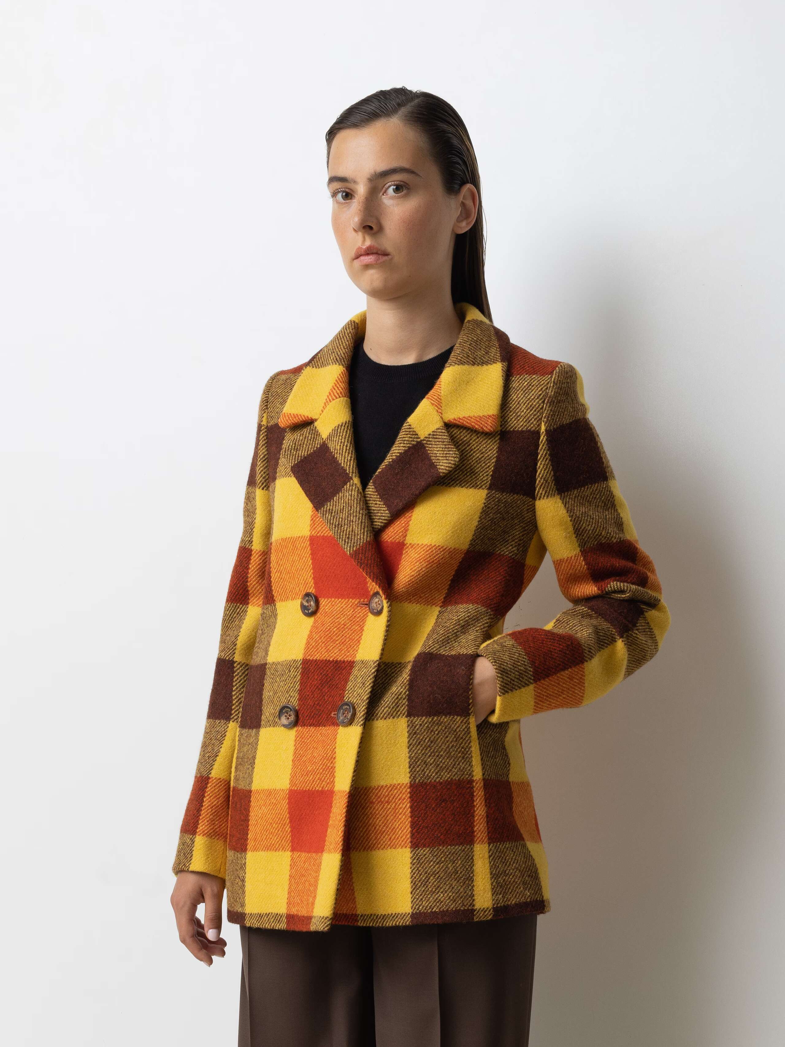 Picture of a female model wearing a colourful wool blazer in combination with classic wool trousers