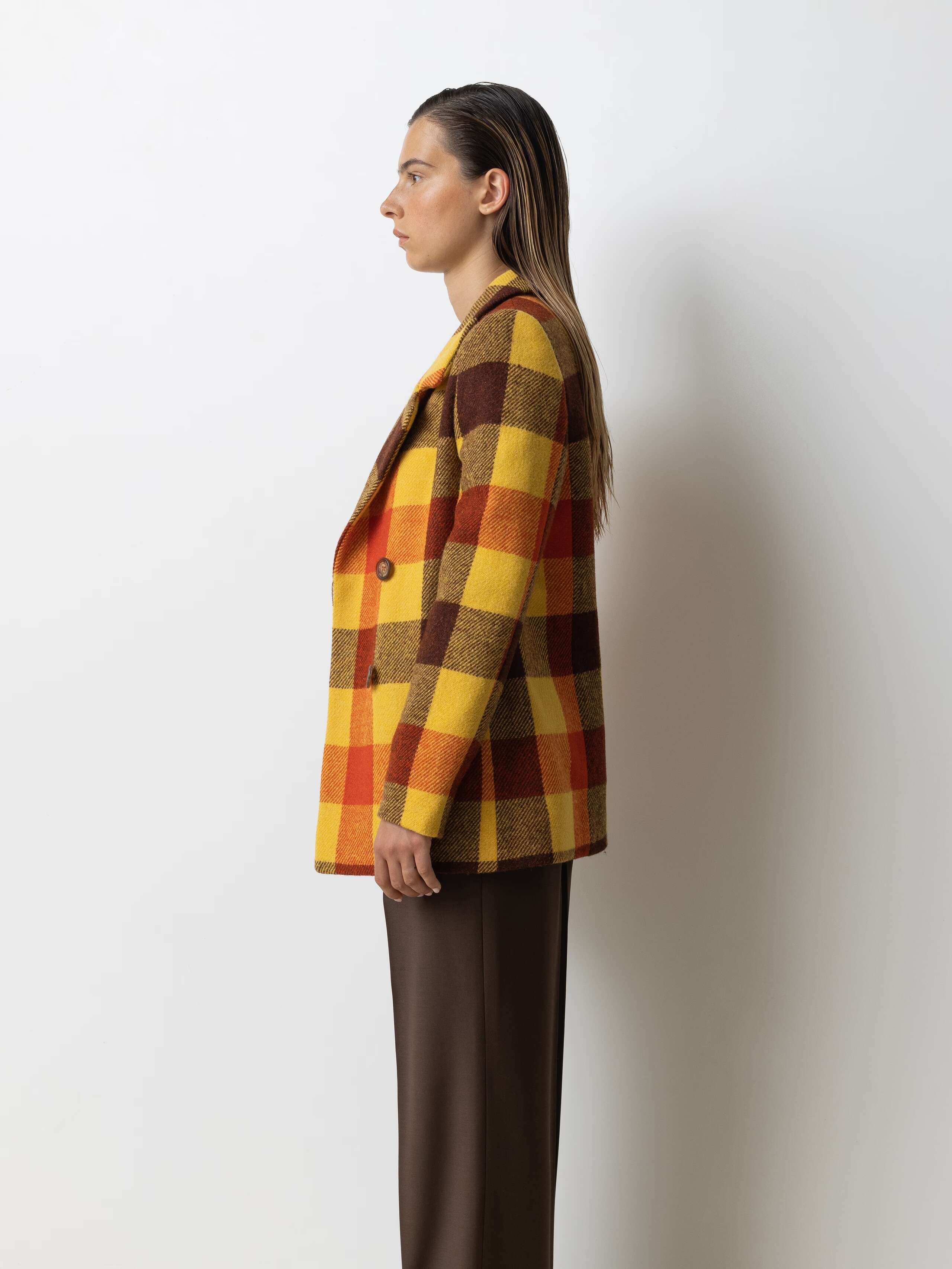 Picture of a female model wearing a colourful wool blazer in combination with classic wool trousers