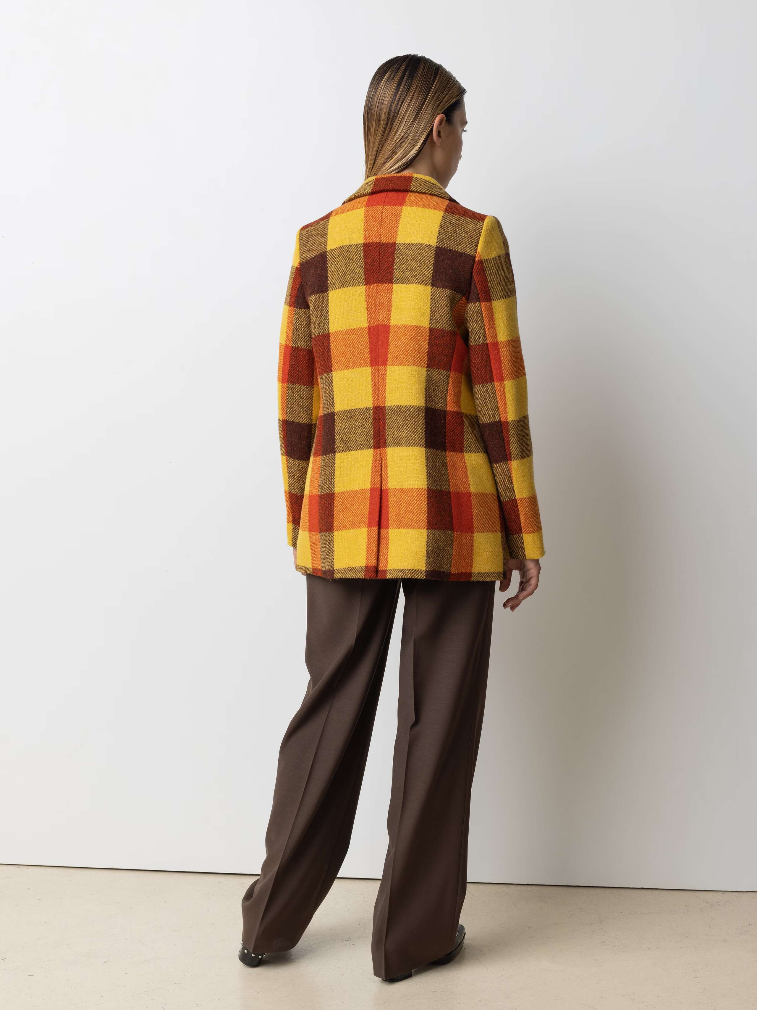 Picture of a female model wearing a colourful wool blazer in combination with classic wool trousers