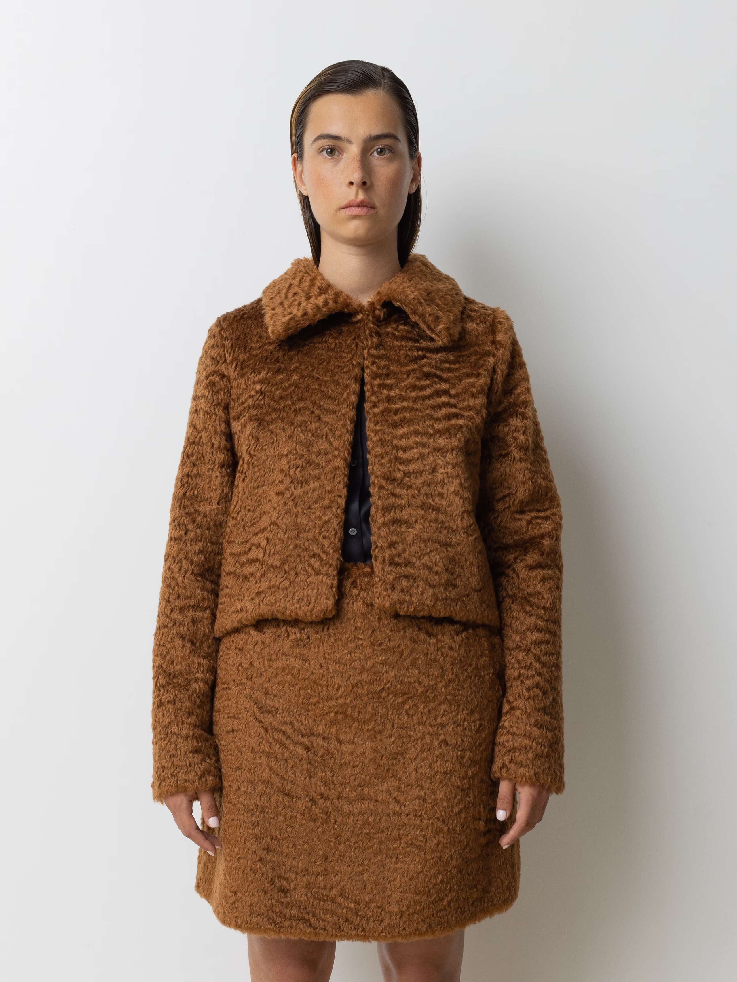 Picture of a female model wearing a combination of a brown mohair wool jacket and a short skirt