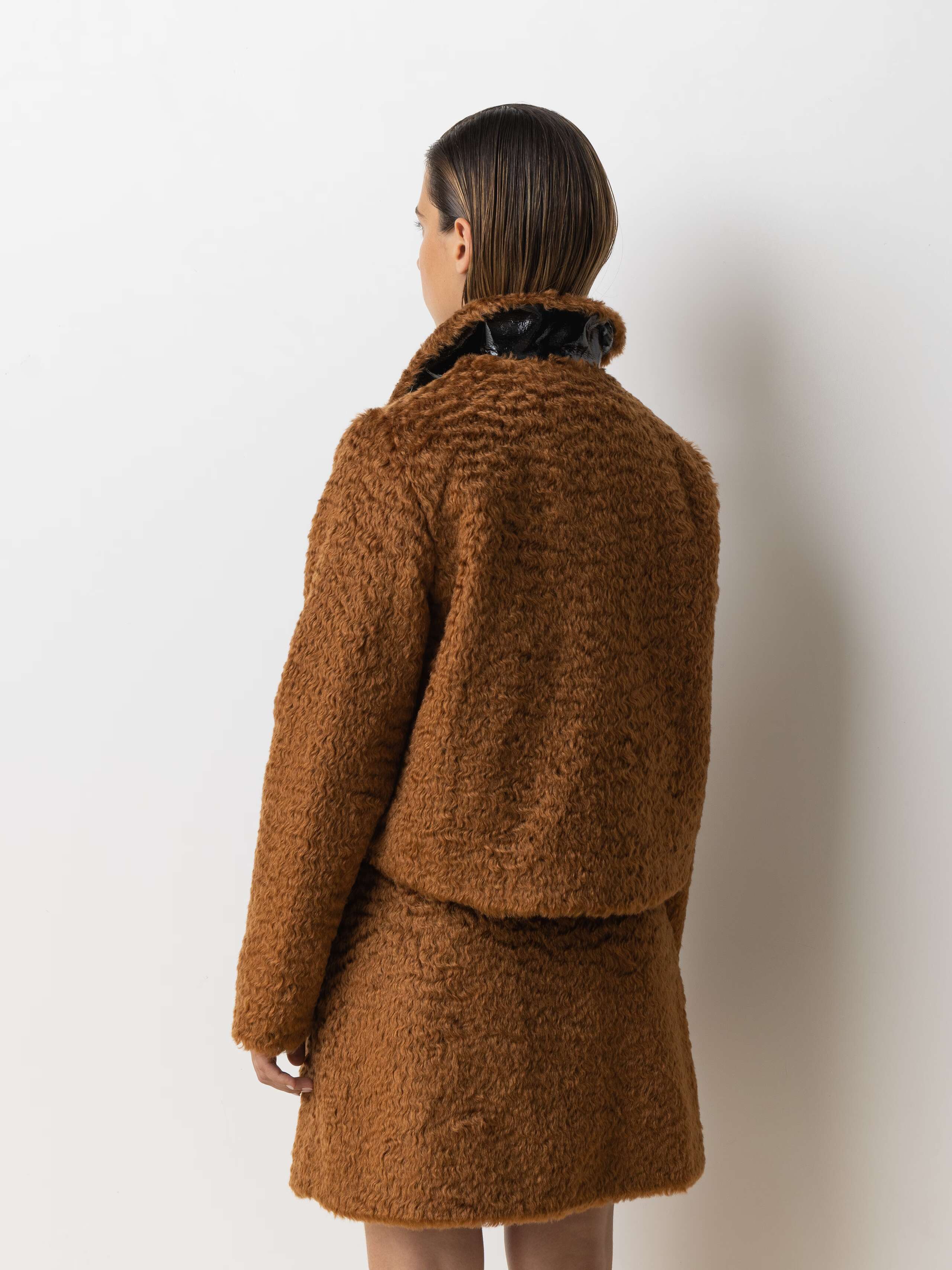 Picture of a female model wearing a combination of a brown mohair wool jacket and a short skirt