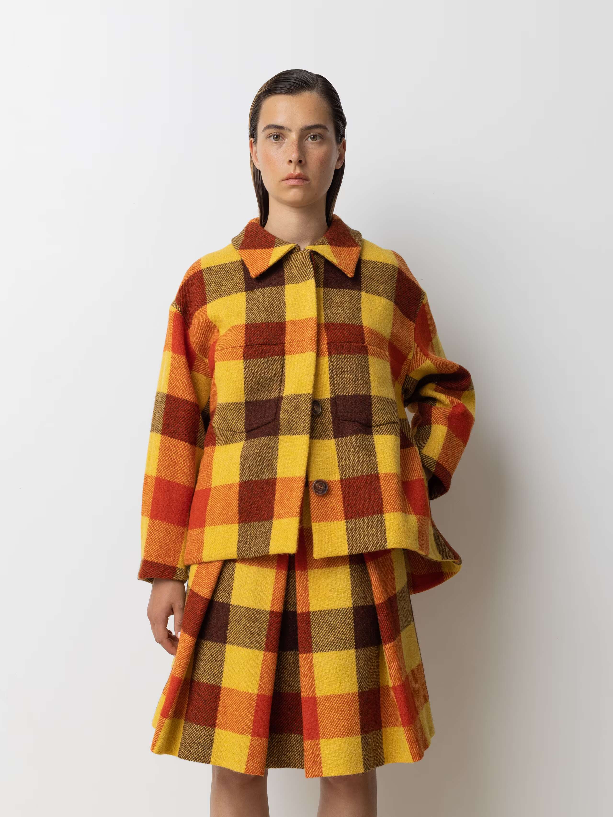 Picture of a female model wearing a wide colourful wool jacket in combination with a matching skirt