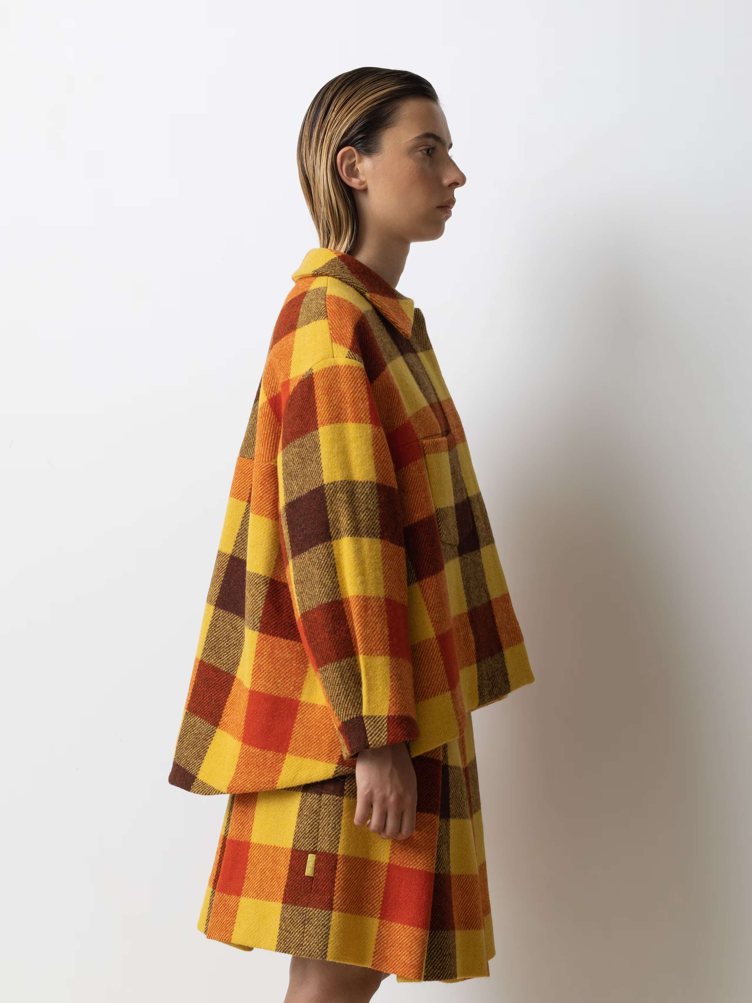 Picture of a female model wearing a wide colourful wool jacket in combination with a matching skirt