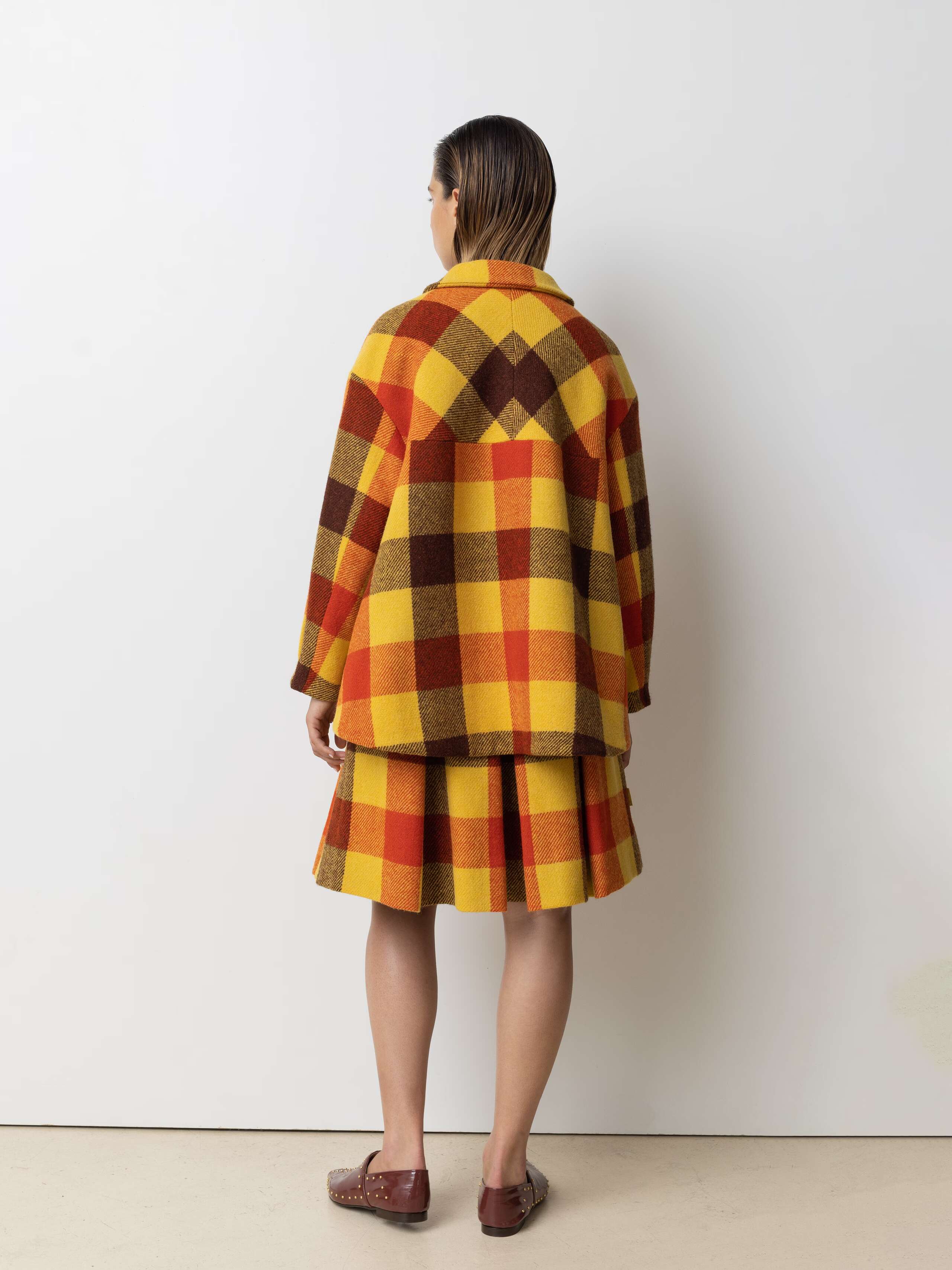 Picture of a female model wearing a wide colourful wool jacket in combination with a matching skirt