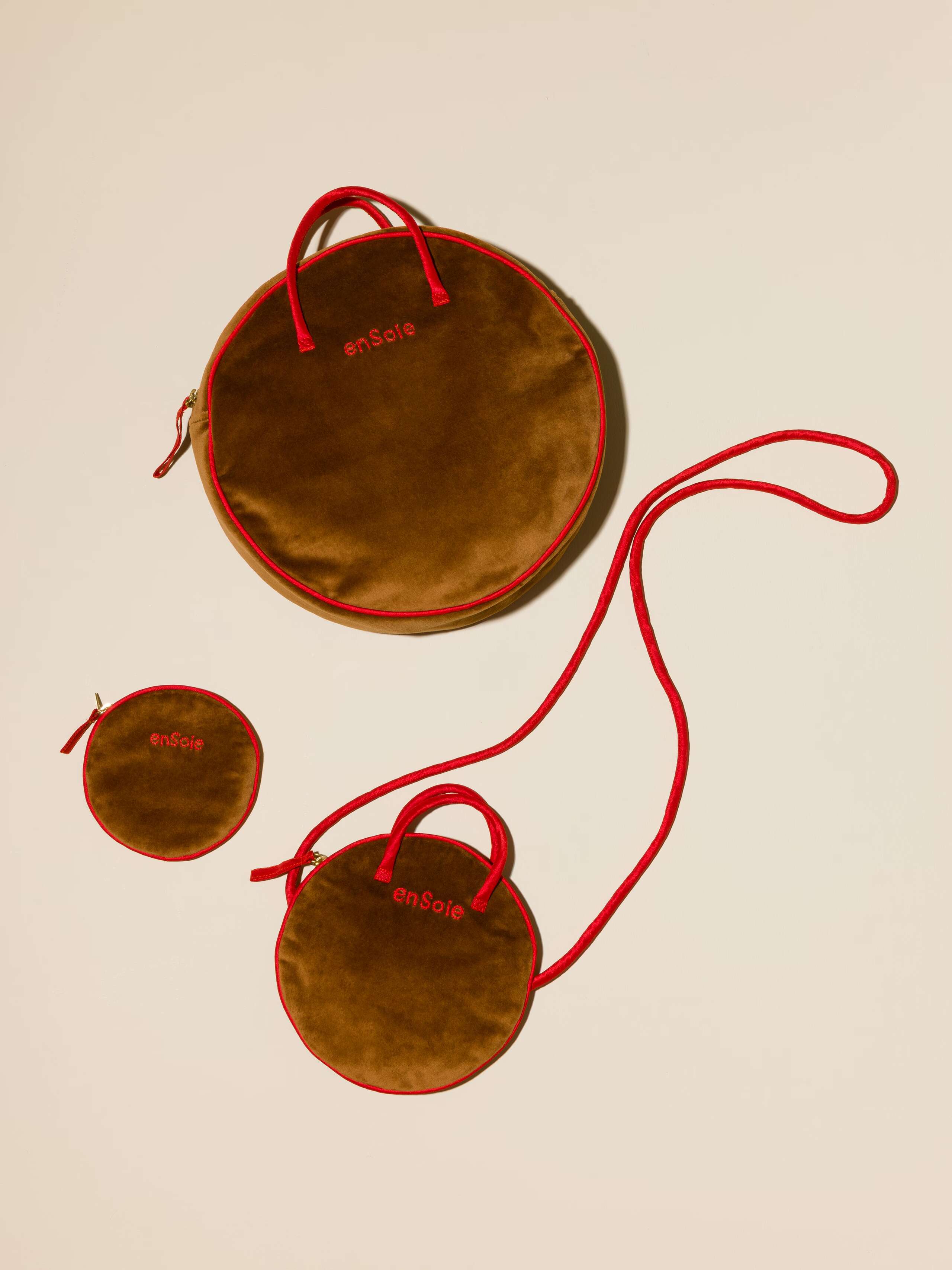 Picture of three round bags in three different sizes made of brown velvet featuring red silk handles