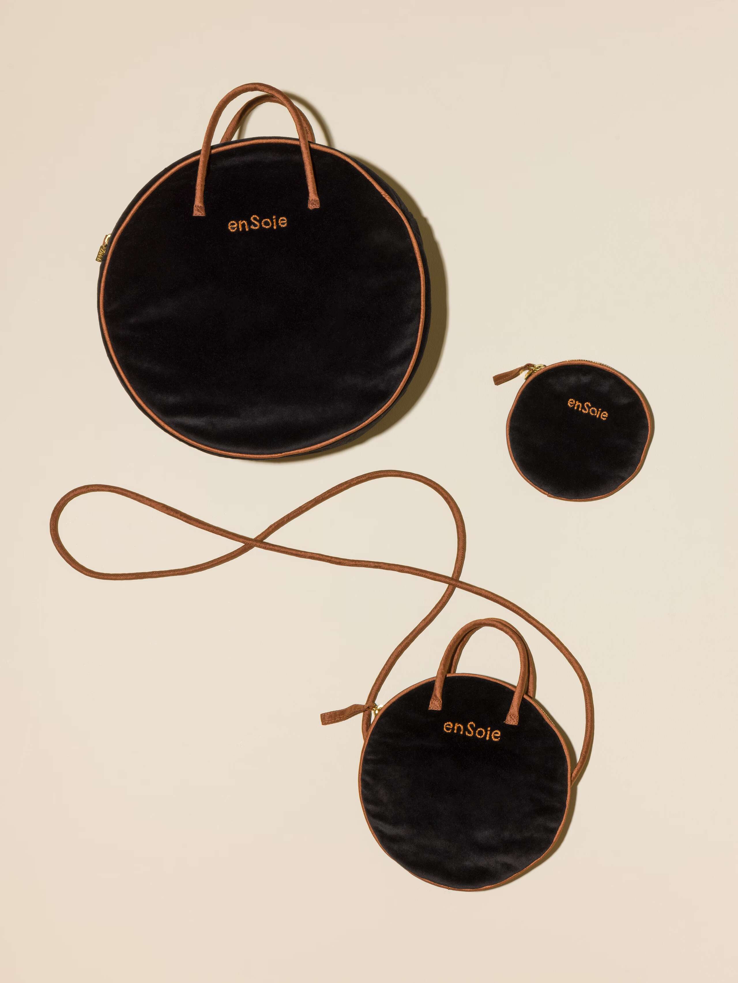 Picture of three round bags in three different sizes made of black velvet featuring brown silk handles