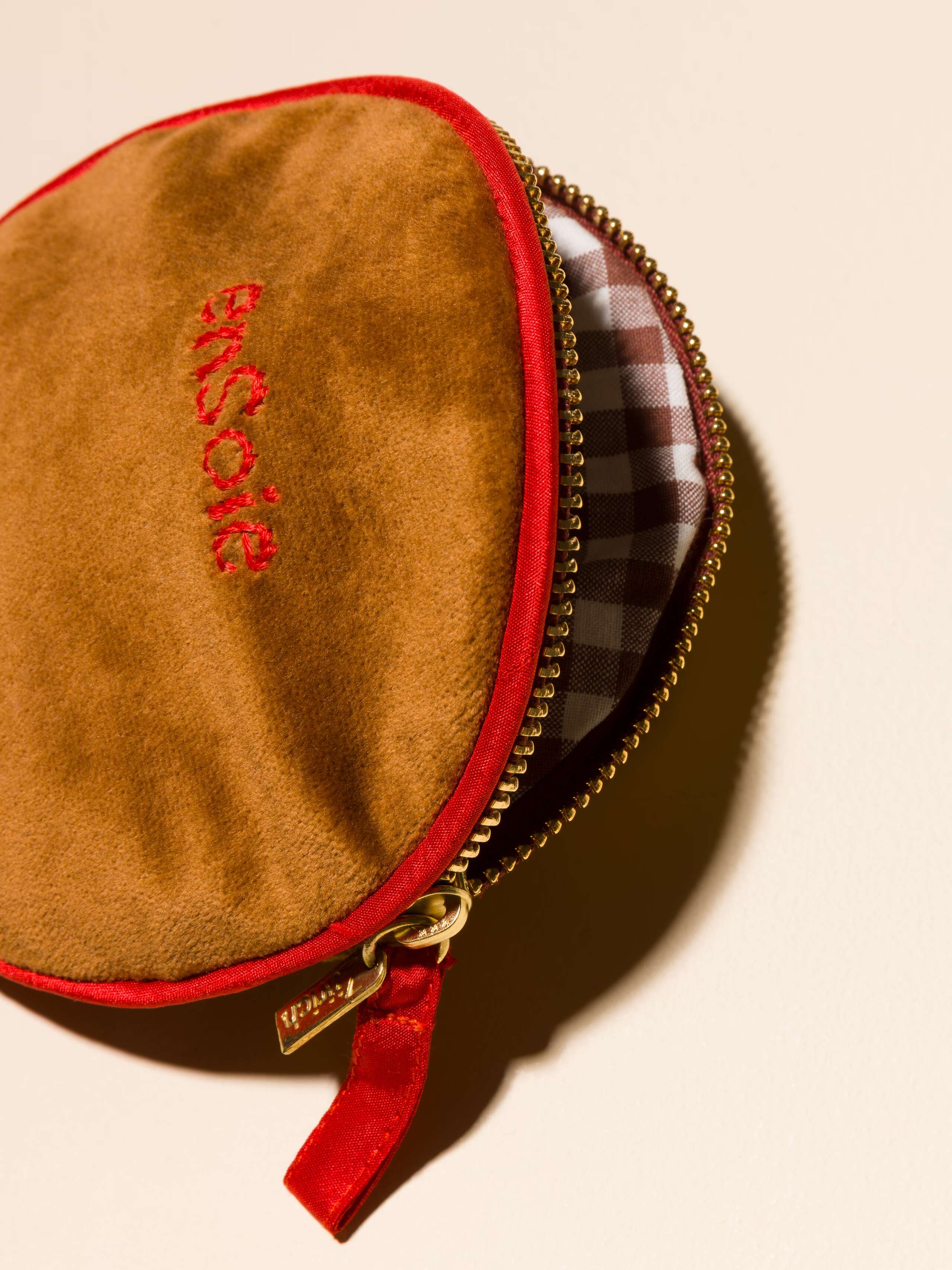 Picture of a detail of a brown velvet bag featuring red silk borders and a beautiful striped inlay