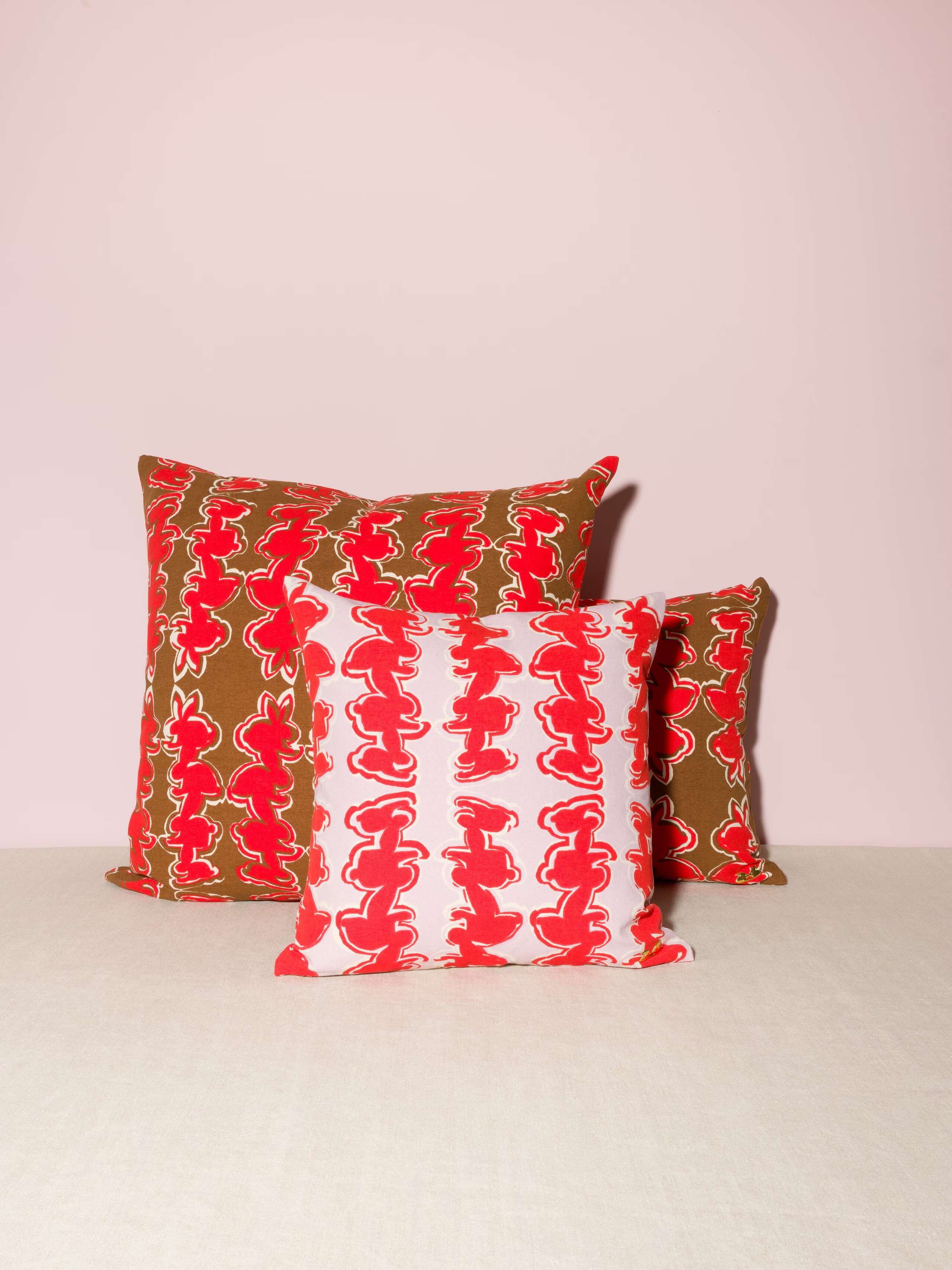 Picture of three pillows in two sizes featuring a beautiful rabbit print in red on a lavender and a brown ground
