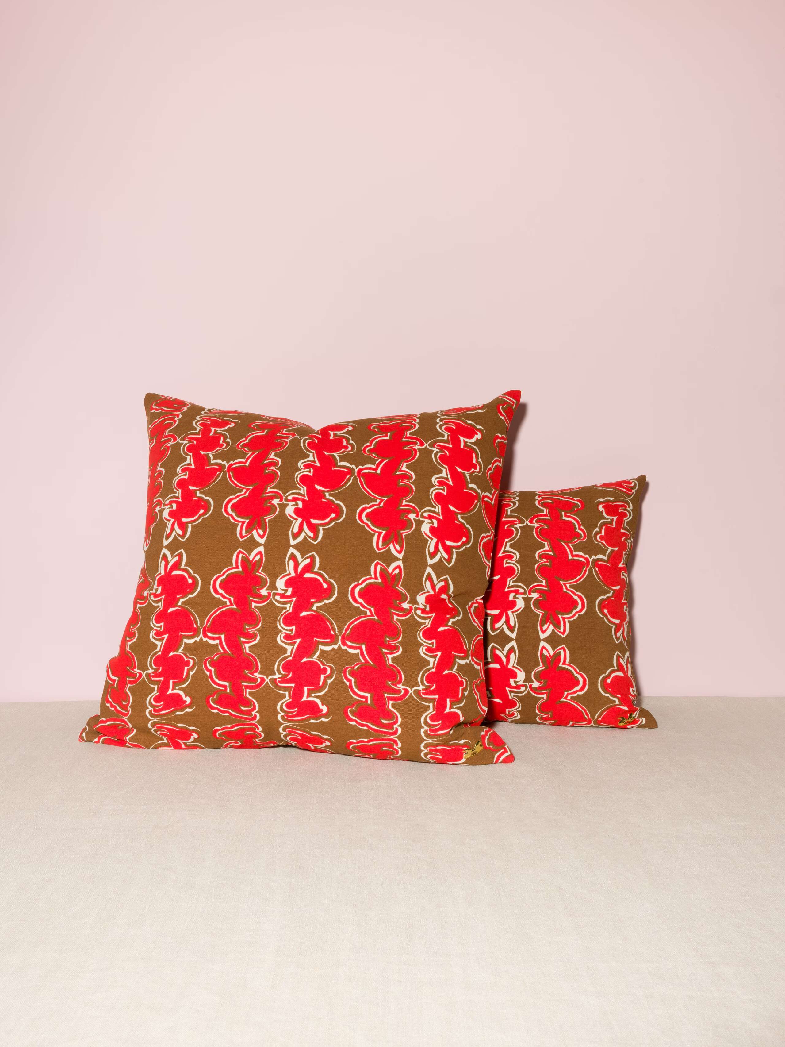 Picture of two pillows in two sizes featuring a beautiful rabbit print in red on a brown ground
