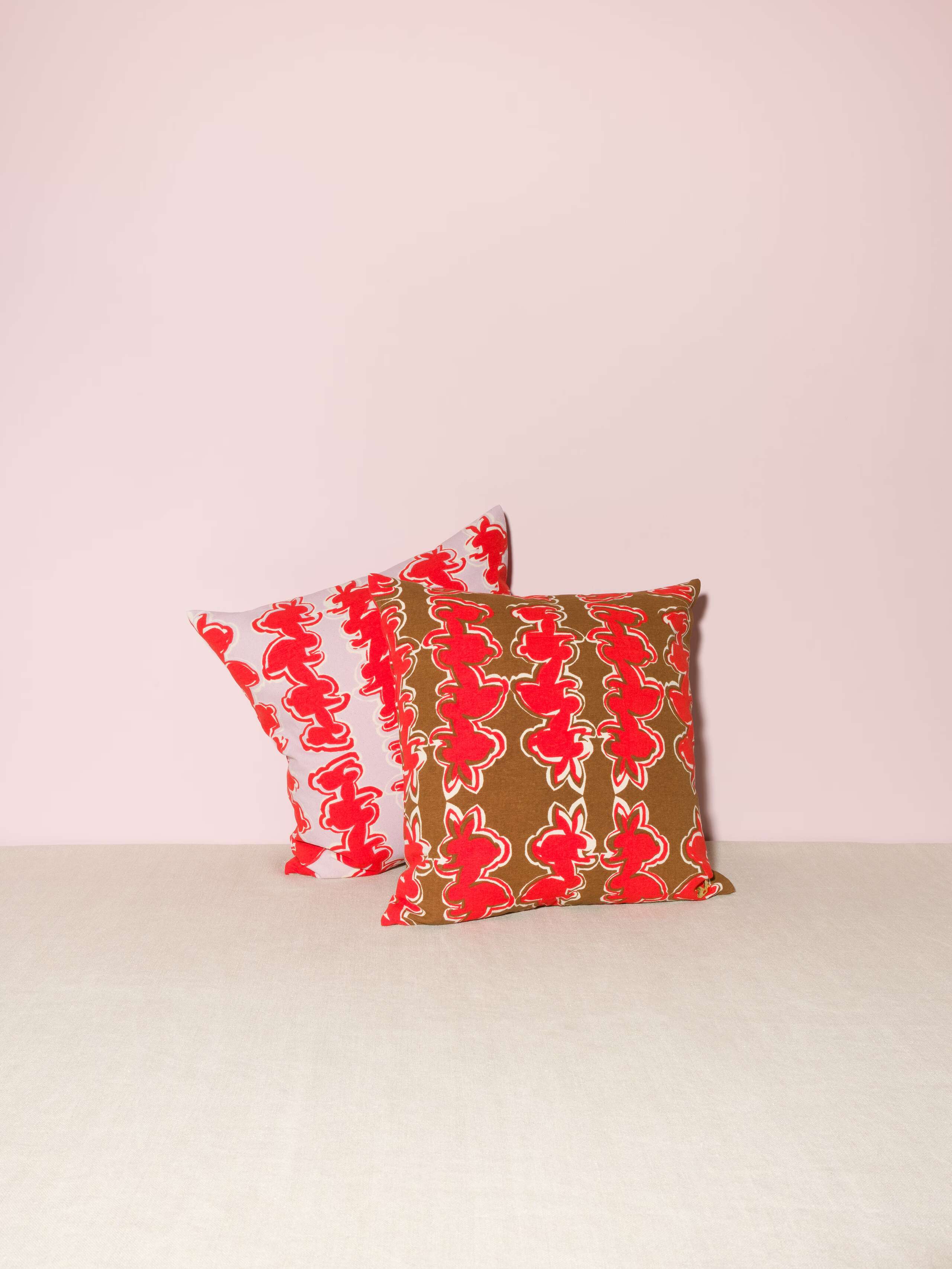 Picture of two pillows featuring a beautiful rabbit print in red on a lavender and a brown ground