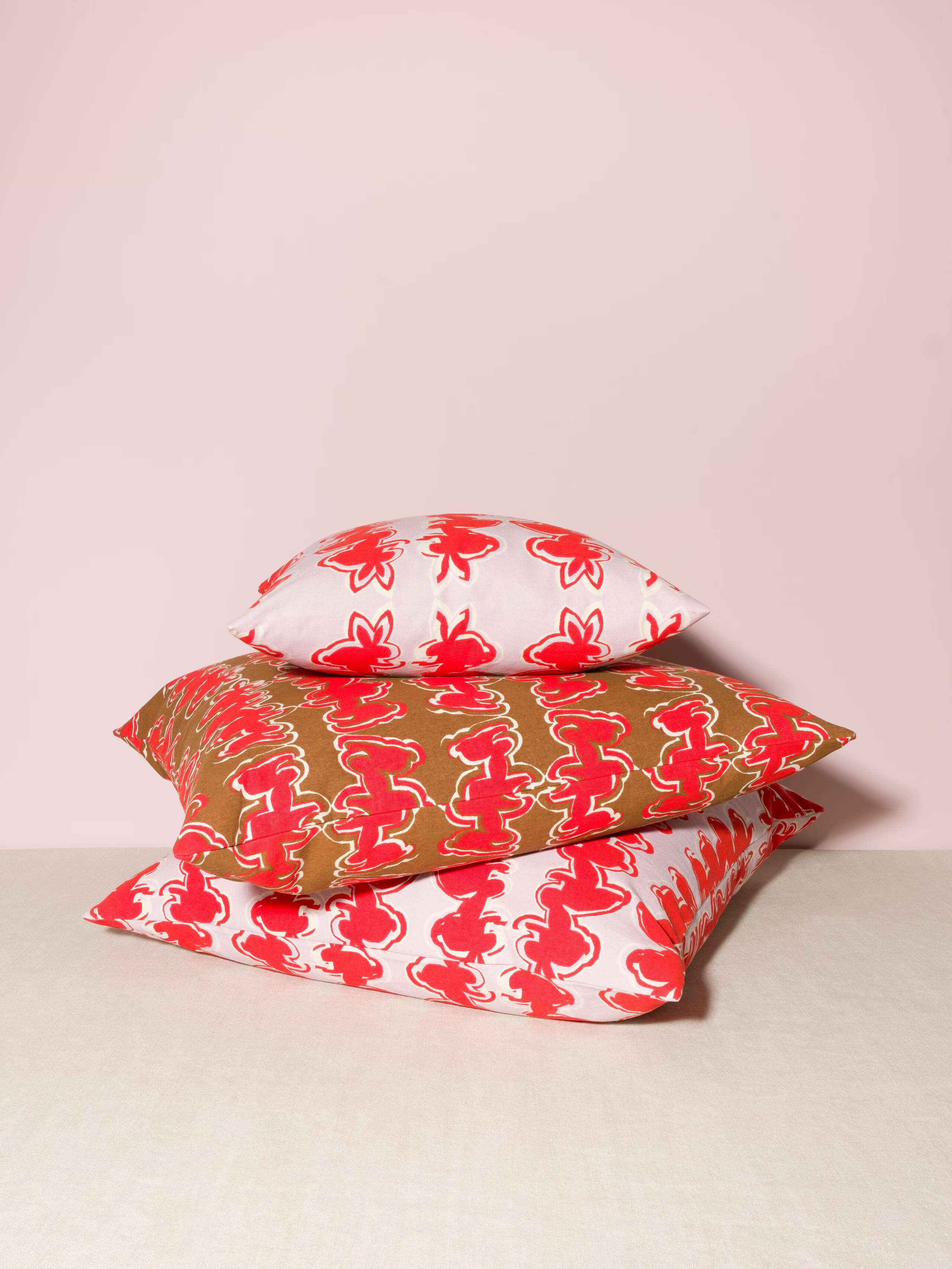 Picture of three pillows featuring a beautiful rabbit print in red on a lavender and a brown ground