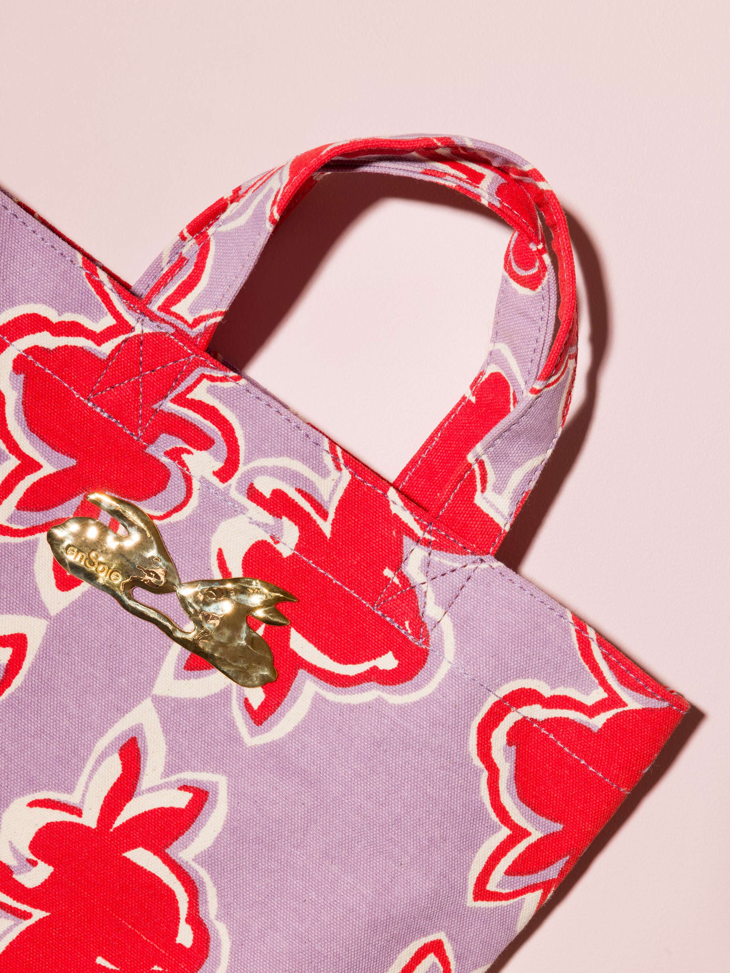 Picture of a detail of a cute cotton canvas bag in a beautiful lavender shade featuring a kissing rabbit brass tag
