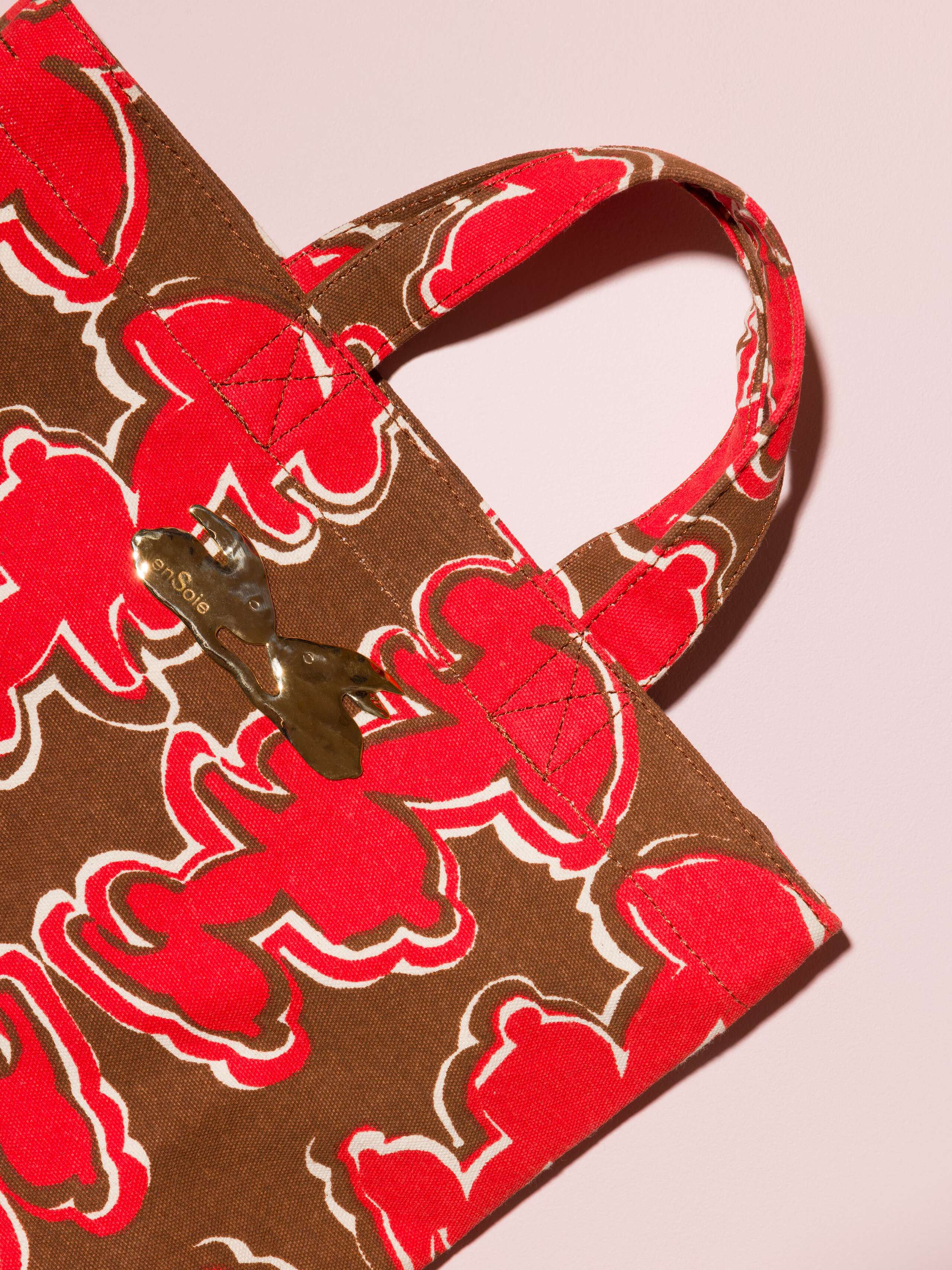 Picture of a detail of a cute cotton canvas bag in a beautiful brown shade featuring a kissing rabbit brass tag
