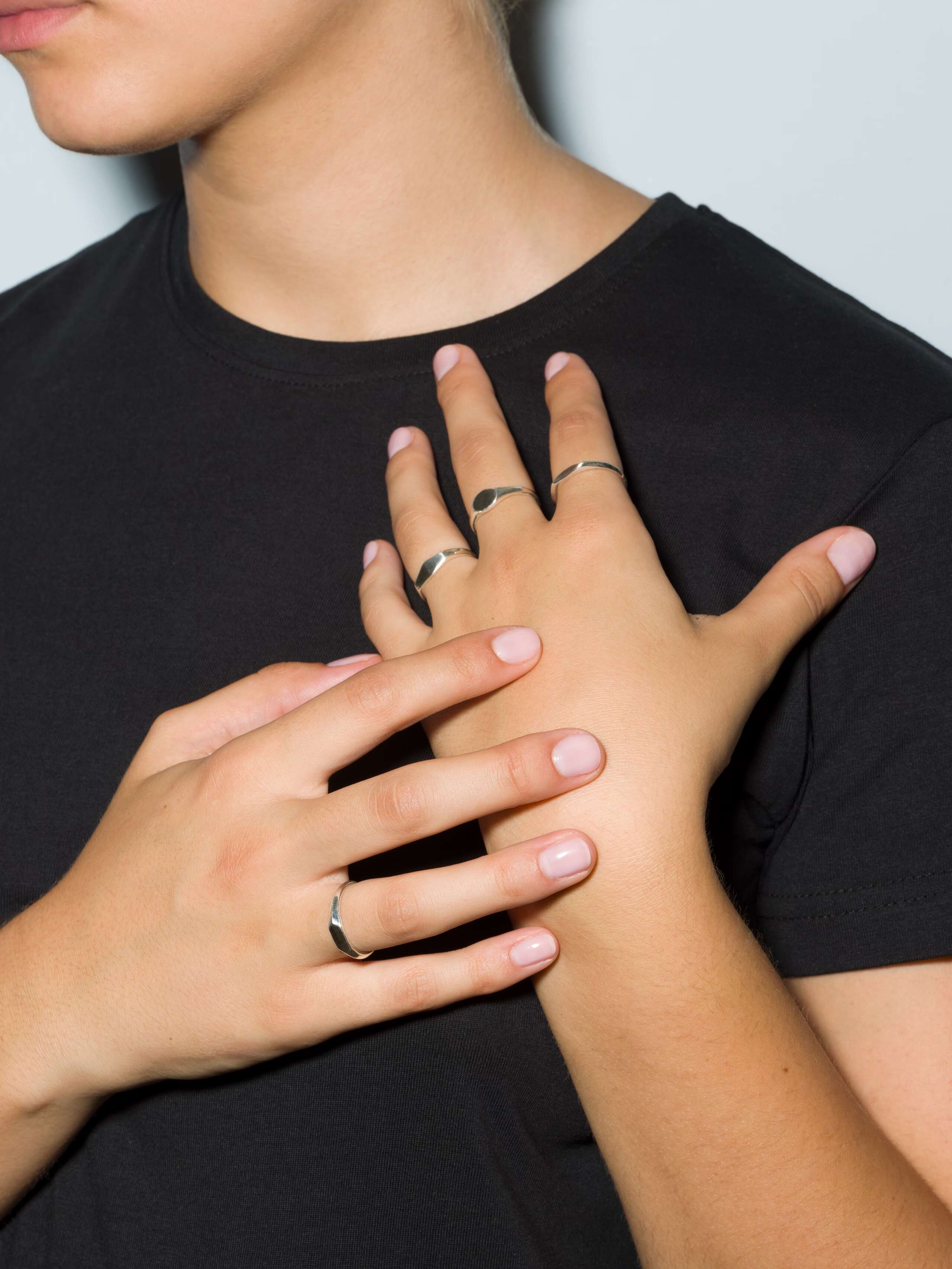 Group of small sterling silver signet rings called Ida on a set of hands