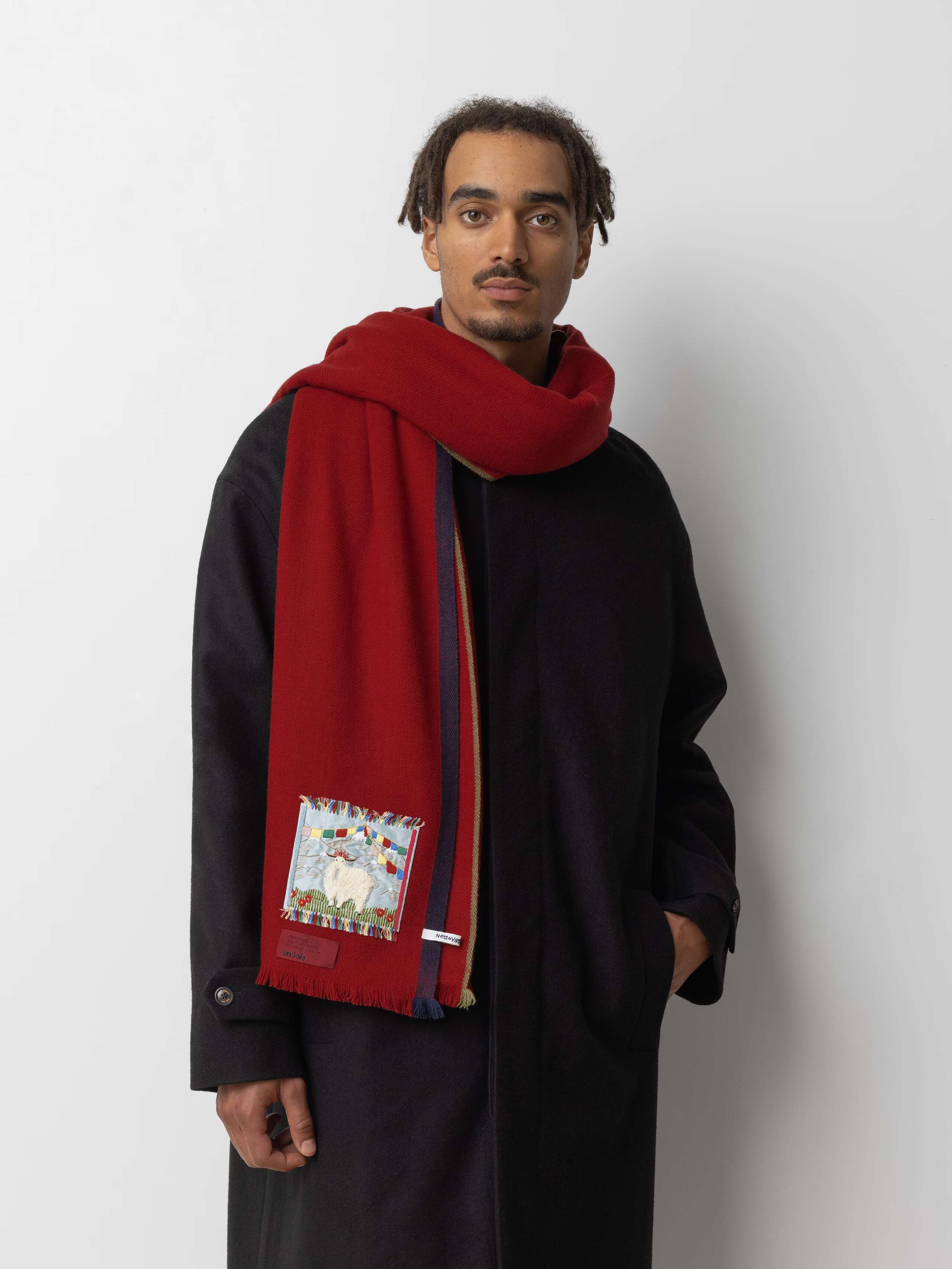 Picture of a male model wearing a black wool coat and a red cashmere scarf