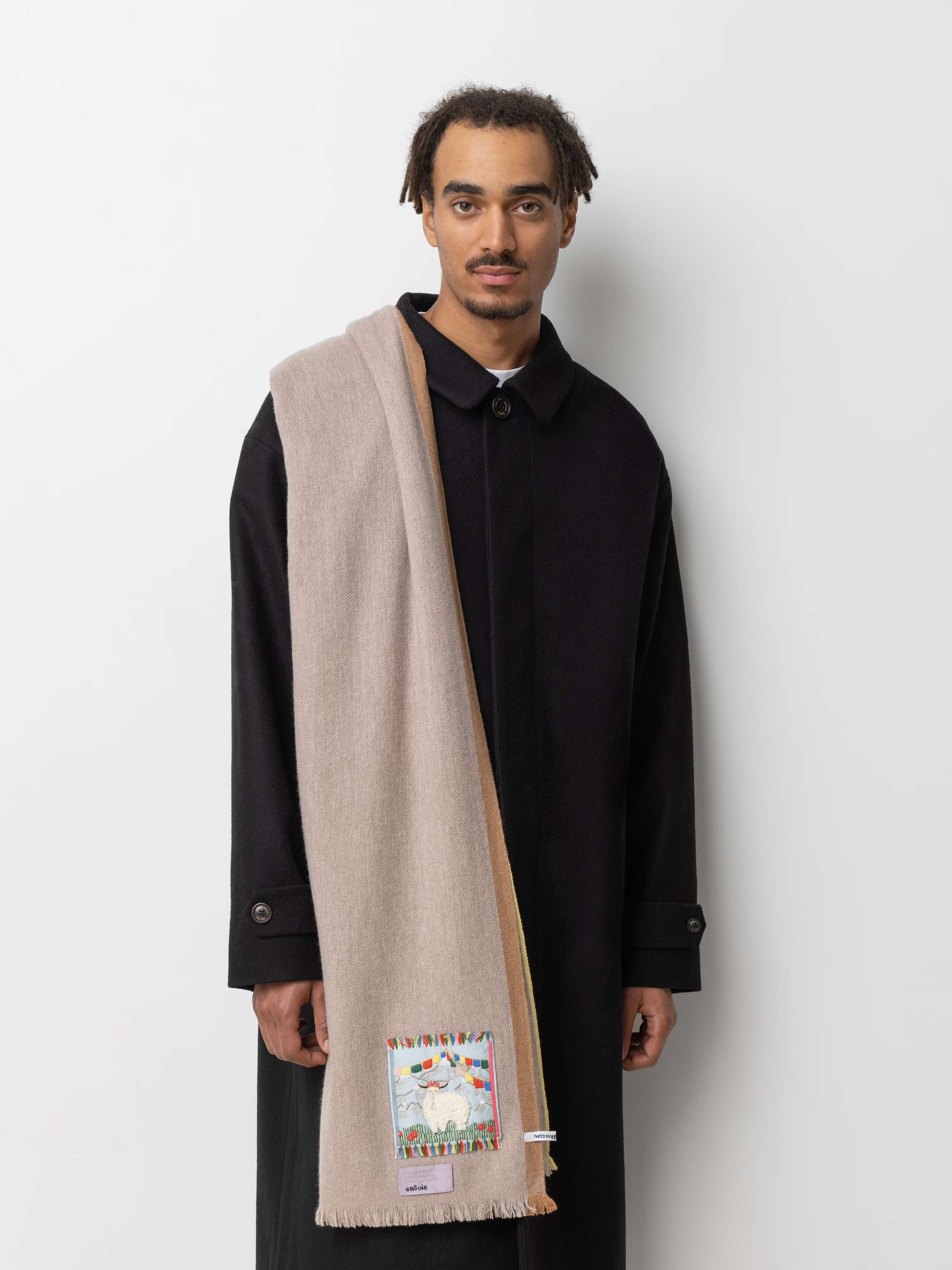 Picture of a male model wearing a black winter coat and a light beige cashmere scarf
