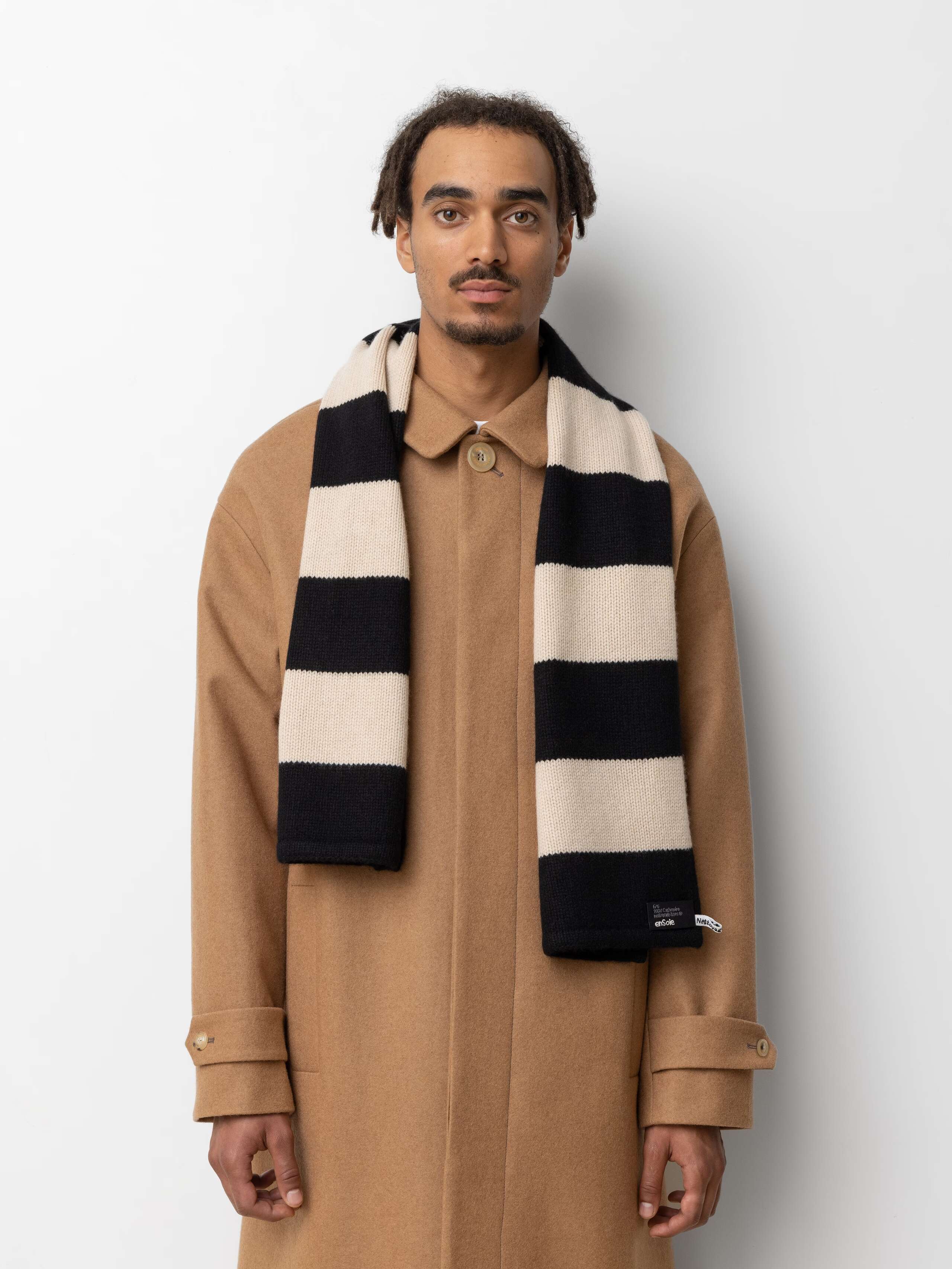 Picture of a male model wearing a beige winter coat and a striped cashmere scarf