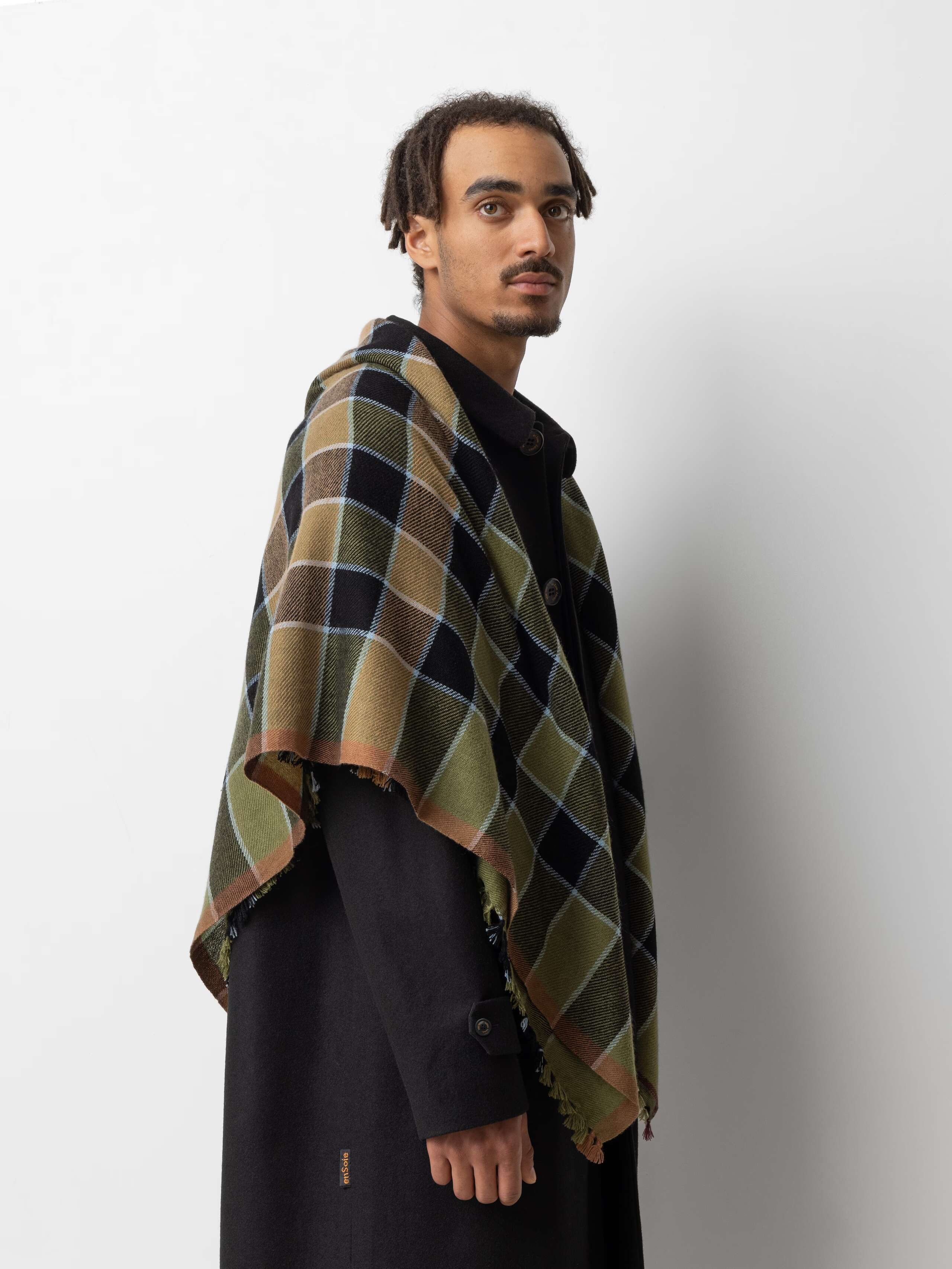 Picture of a male model wearing a black wool coat in combination with a colourful cashmere stole