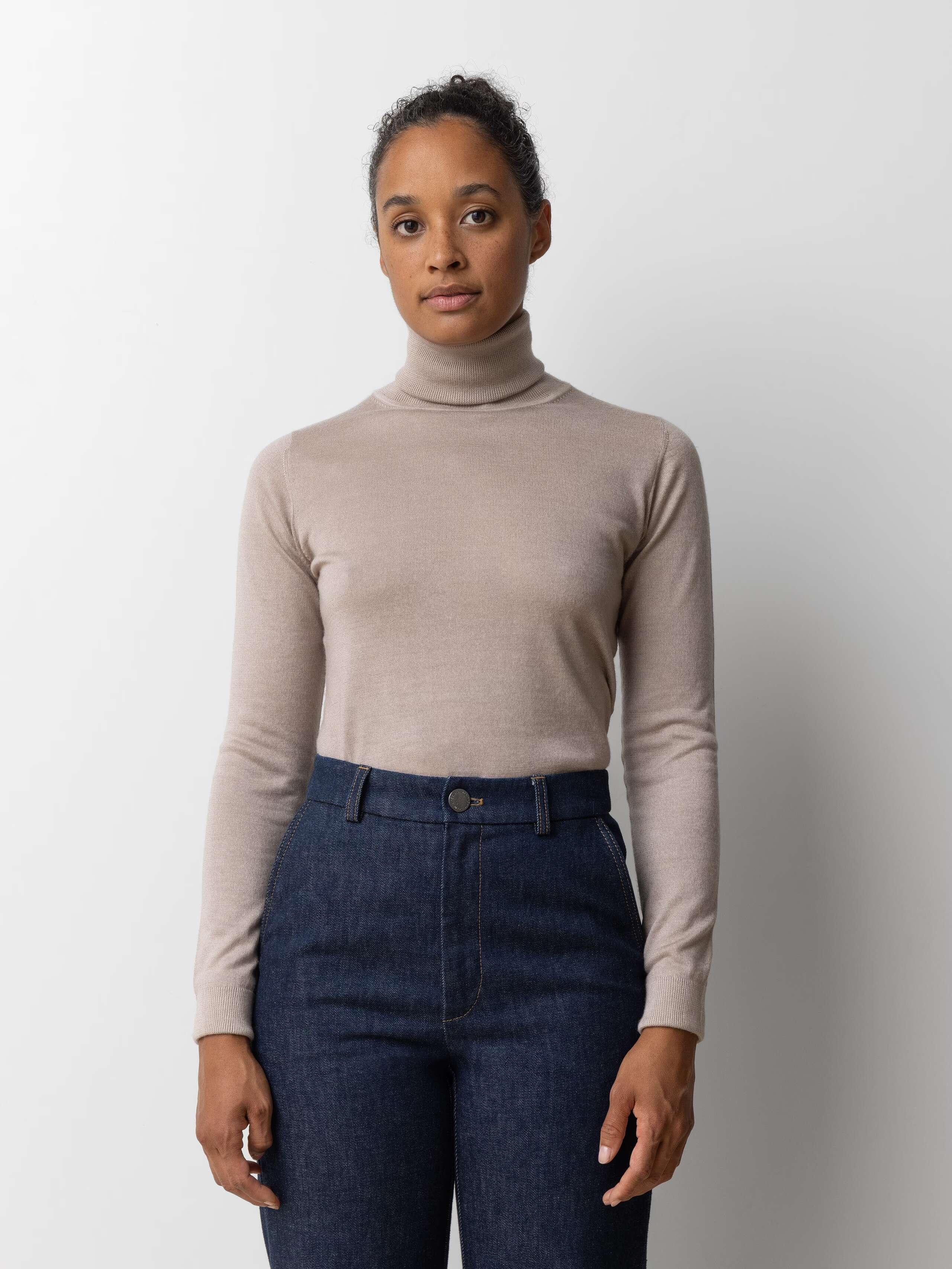 Picture of a female model wearing a beige cashmere turtleneck
