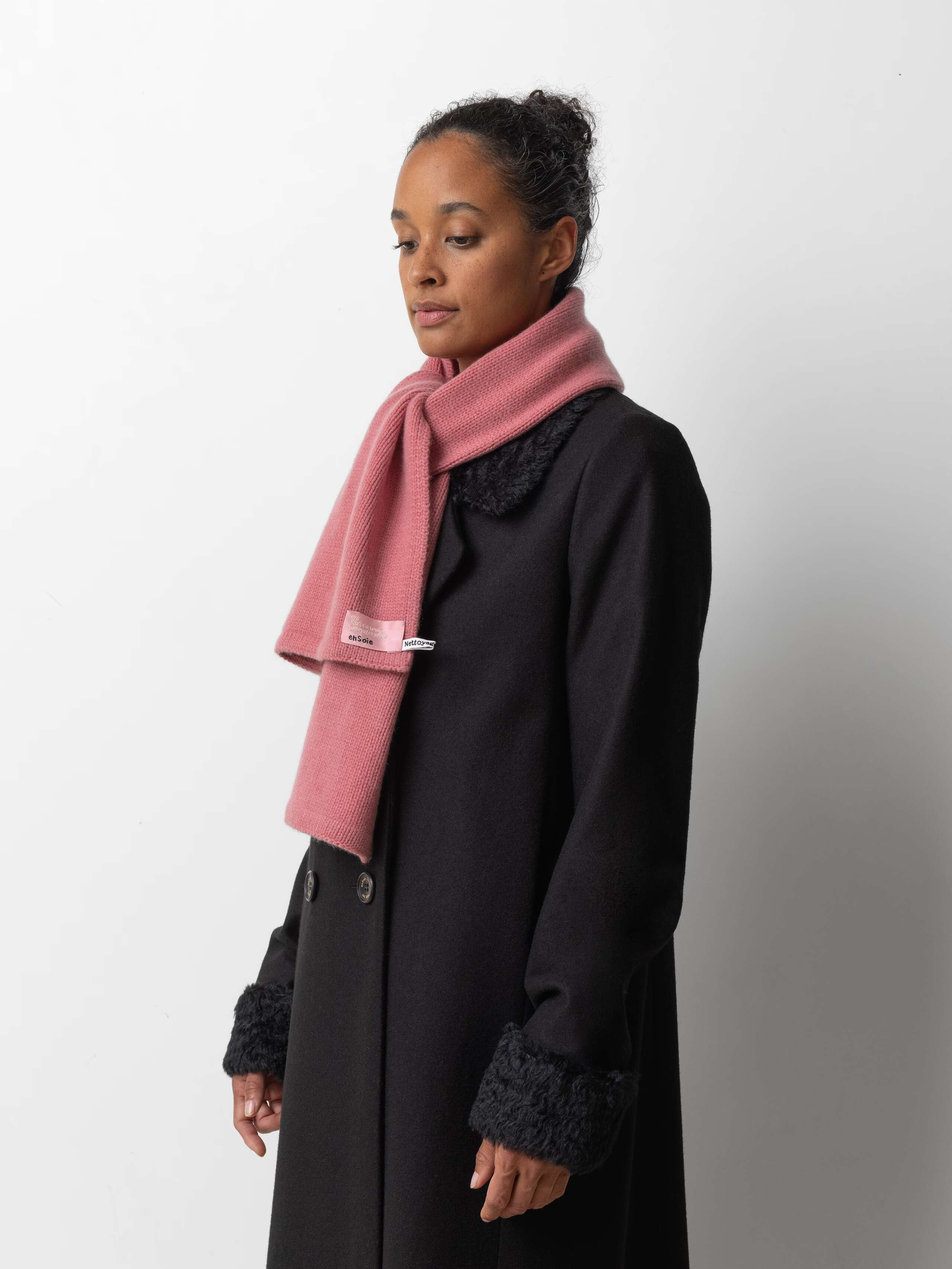 Picture of a female model wearing a black winter coat in combination with a pink cashmere scarf
