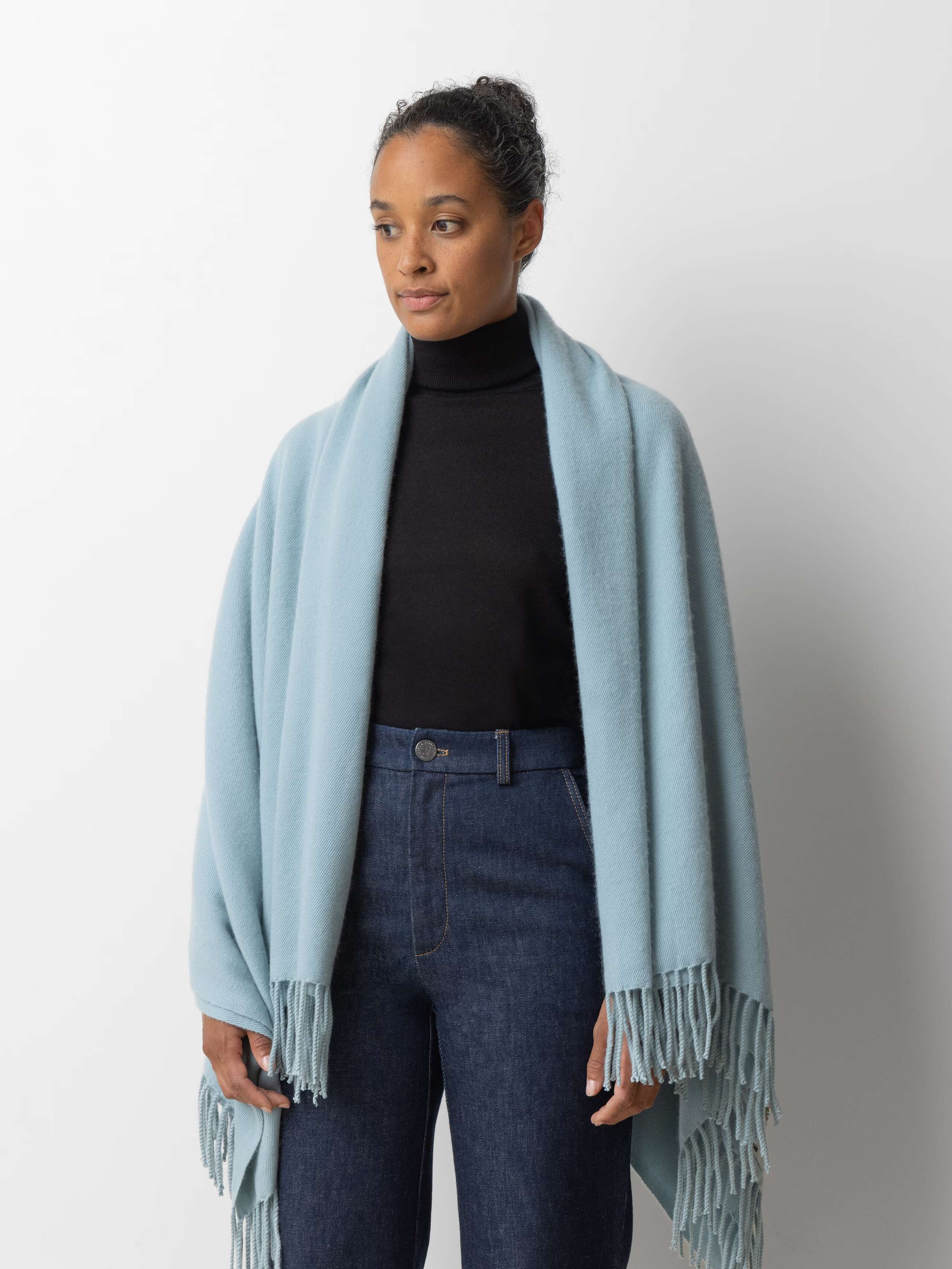 Picture of a female model wearing a jeans in combination with a black turtleneck and a bug light blue cashmere scarf