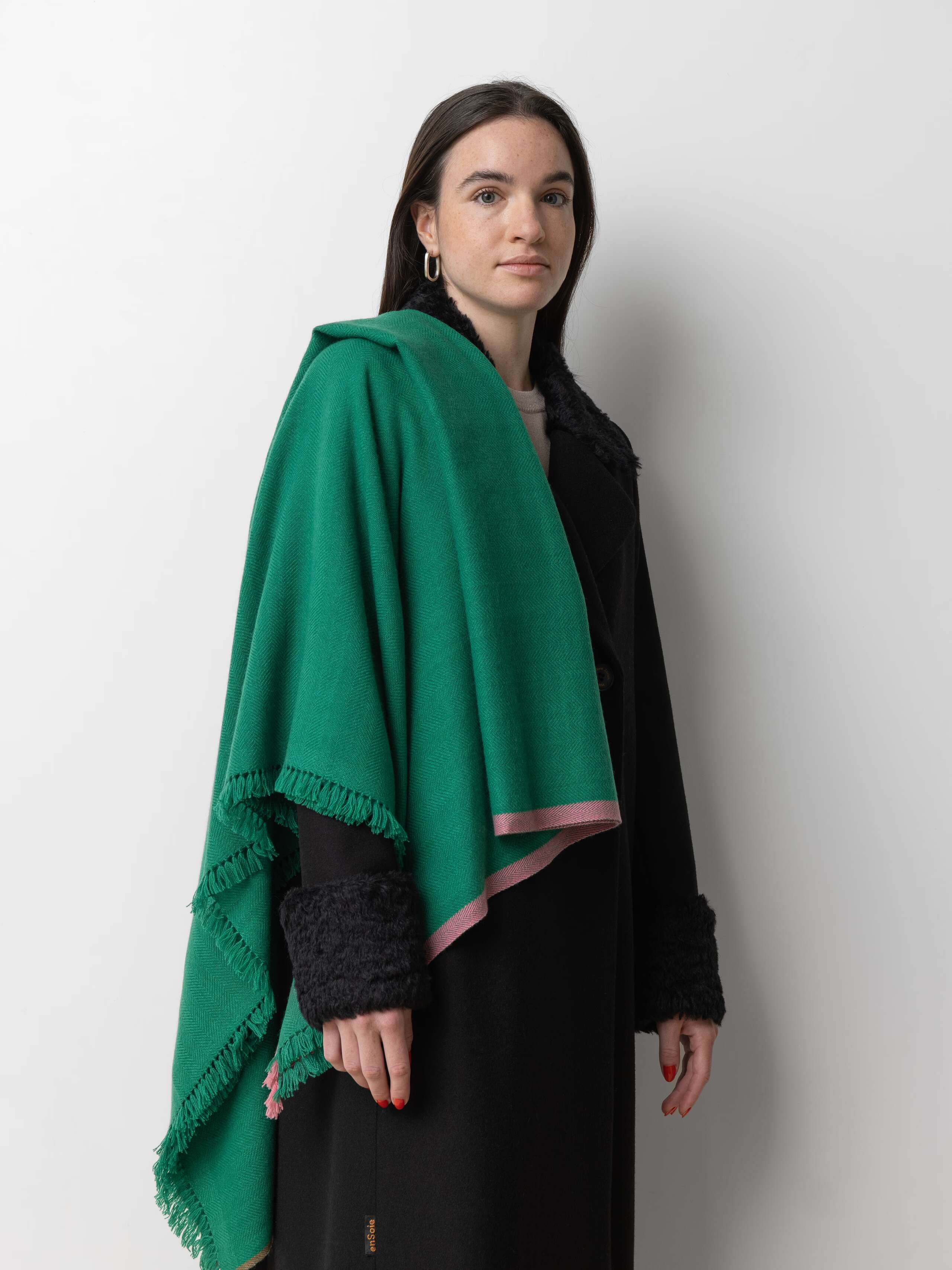 Picture of a model wearing a black winter coat in combination with a green cashmere stole