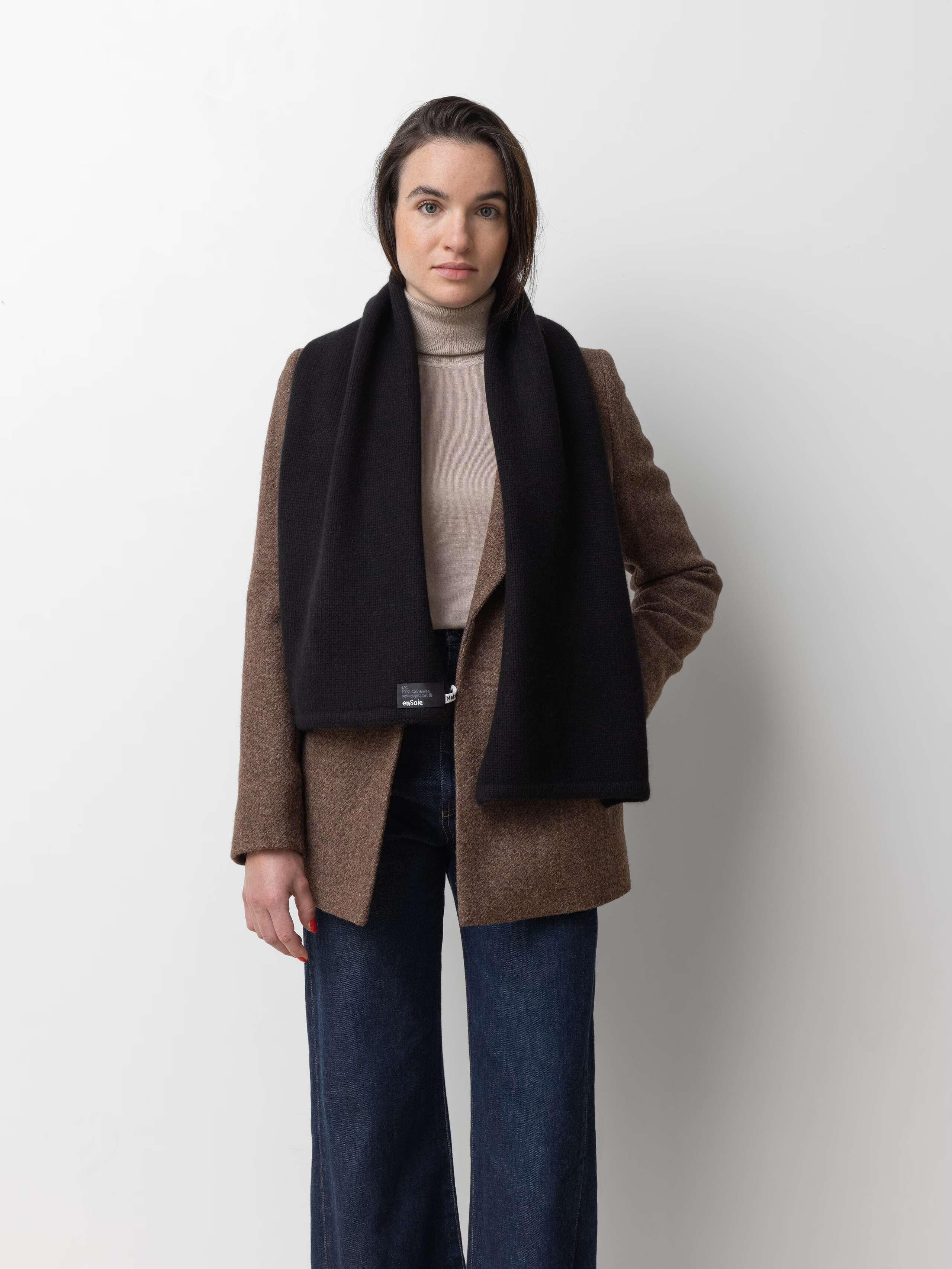 Picture of a female model wearing a brown wool jacket in combination with a jeans and a black cashmere scarf